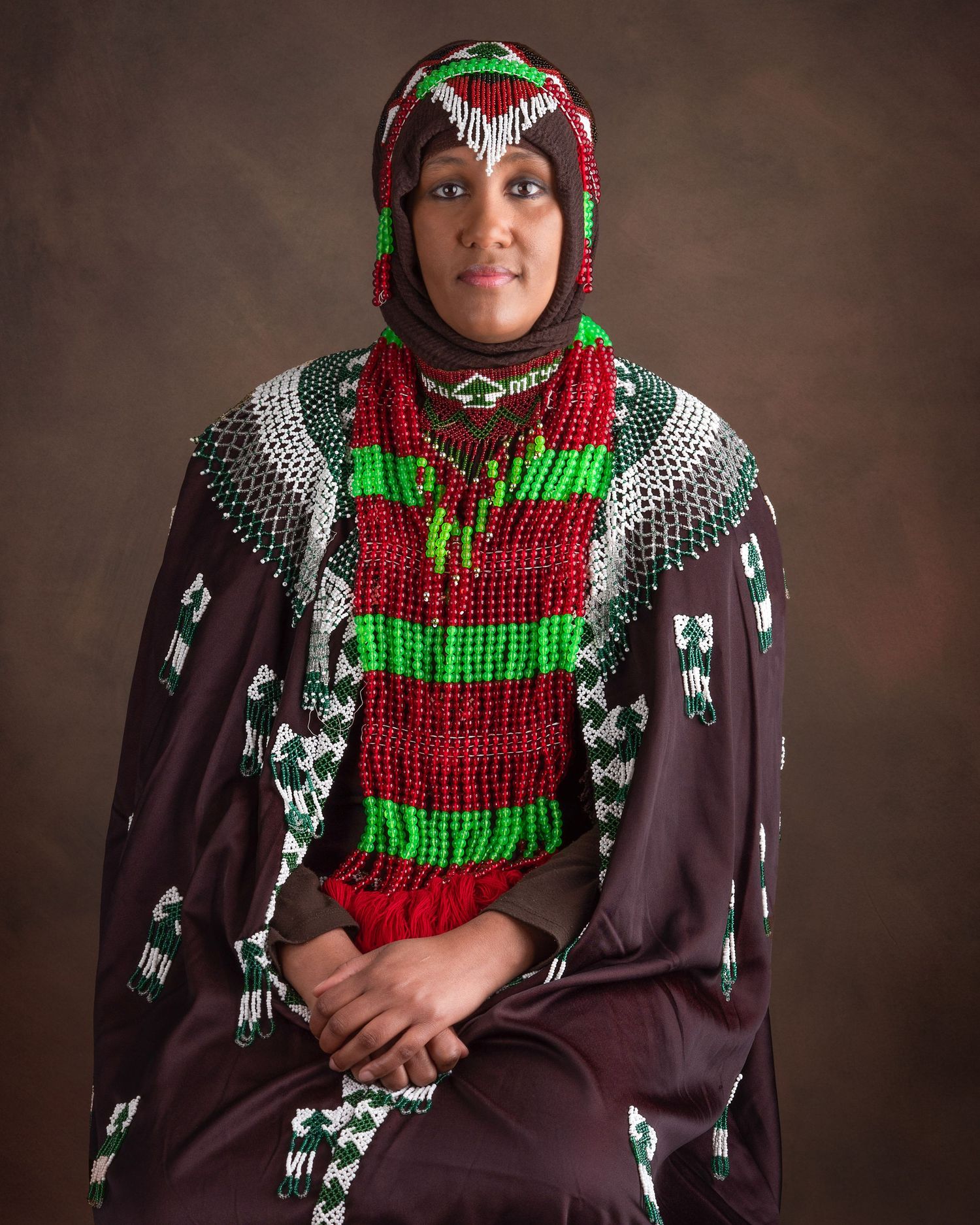 Traditional Middle Eastern clothing with vibrant red and green patterns displayed in a formal portrait setting.