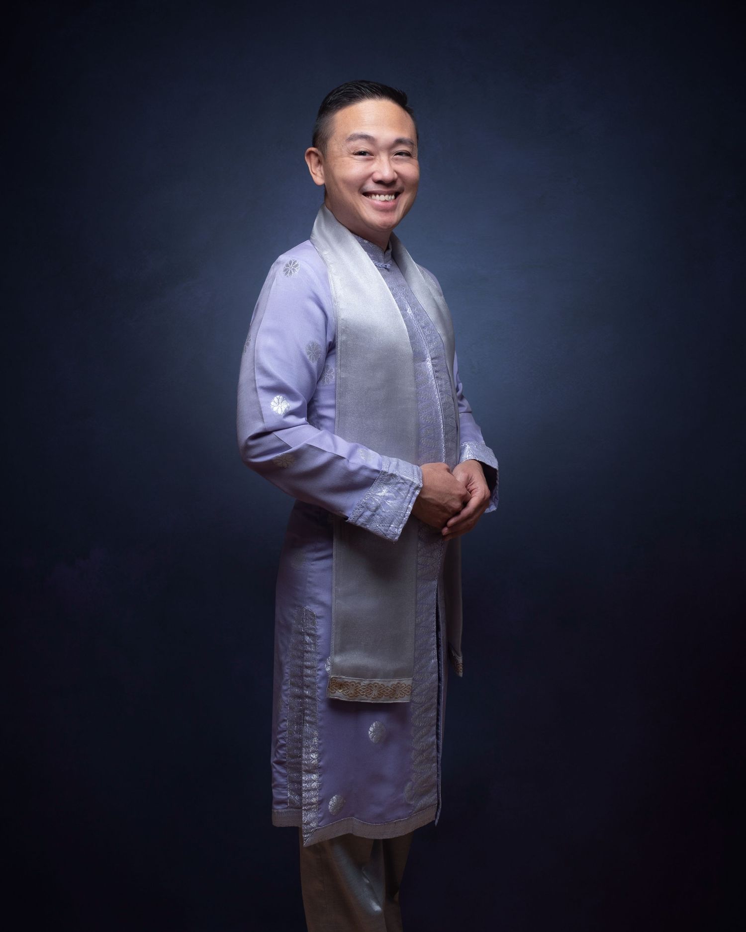Man in light colored traditional clothing and vest poses expressively against dark background in portrait sequence.
