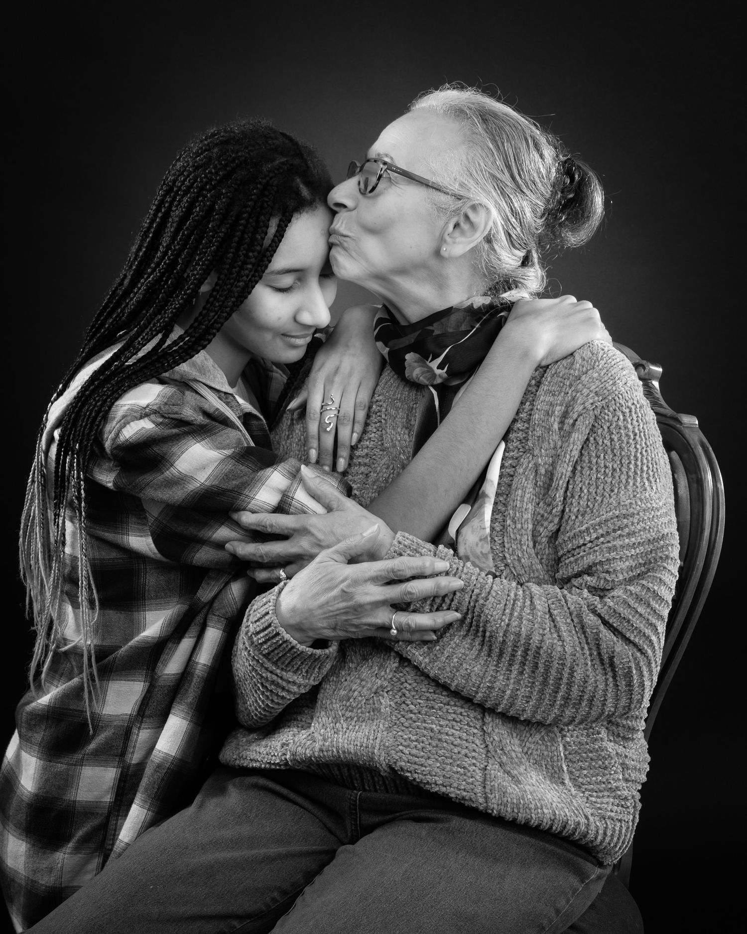 A tender black and white portrait capturing an intimate embrace between a young person and elderly person in sweaters.