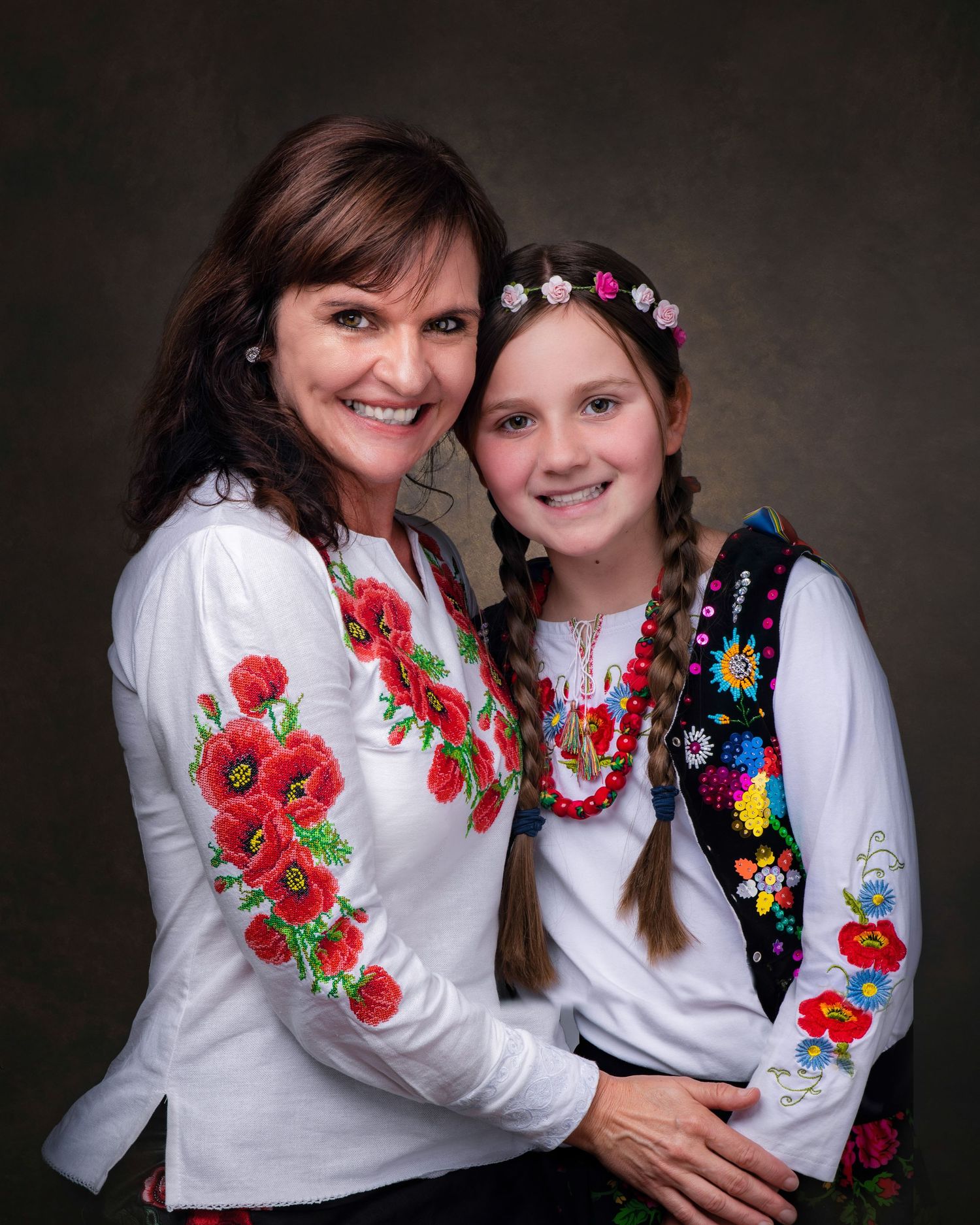 Two people wearing traditional white Ukrainian embroidered vyshyvanka blouses with red floral designs posing for a portrait.