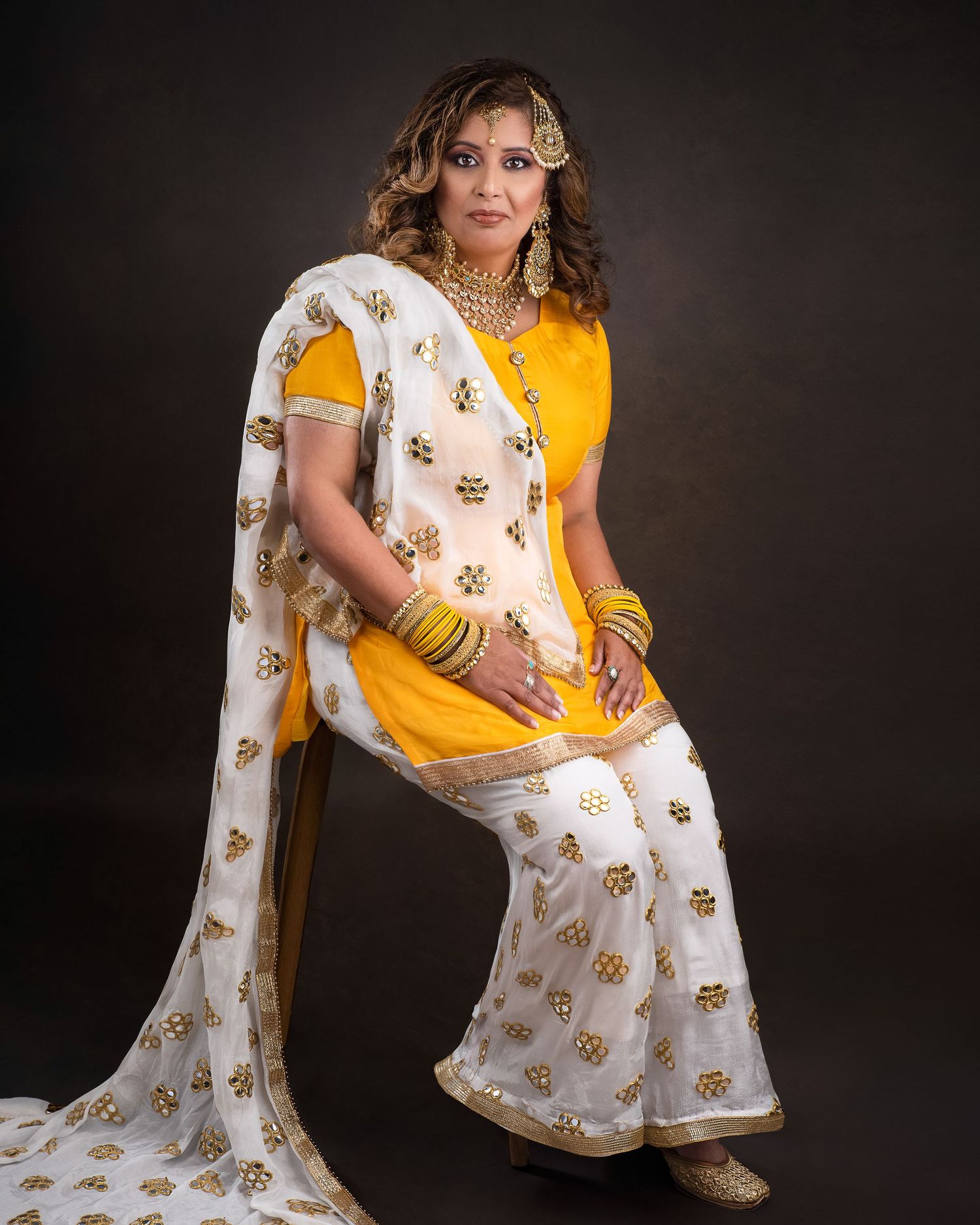 Person wearing white and gold saree with intricate patterns poses against dark background in multiple artistic shots.