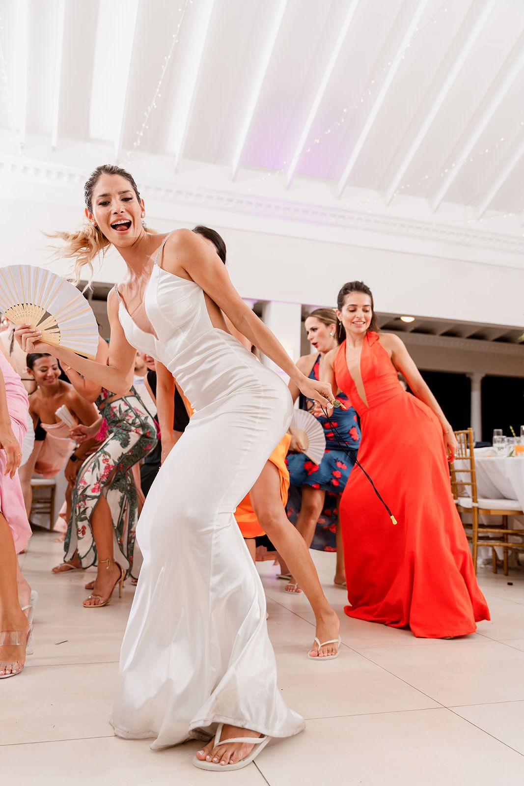 Bride dances energetically while holding a decorative fan.
