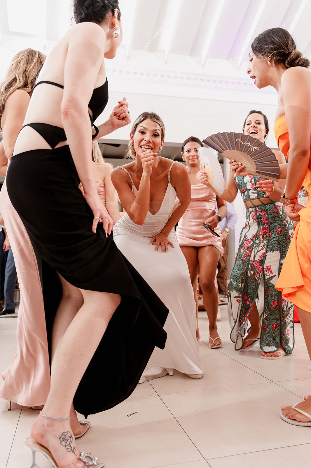 Wedding guests dancing and laughing together on a white tiled dance floor at a reception.