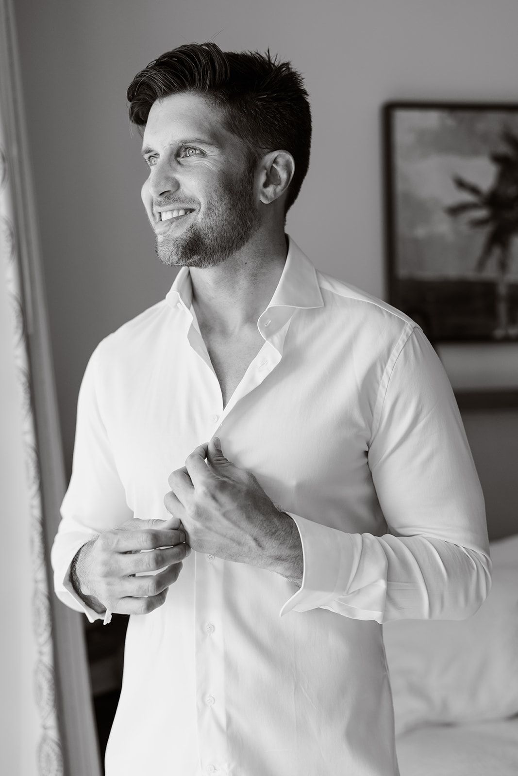 Candid black and white portrait of person in white shirt looking out window.