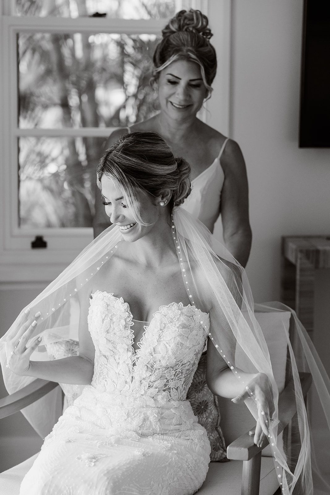 Elegant wedding preparation moment in black and white with lace dress details.