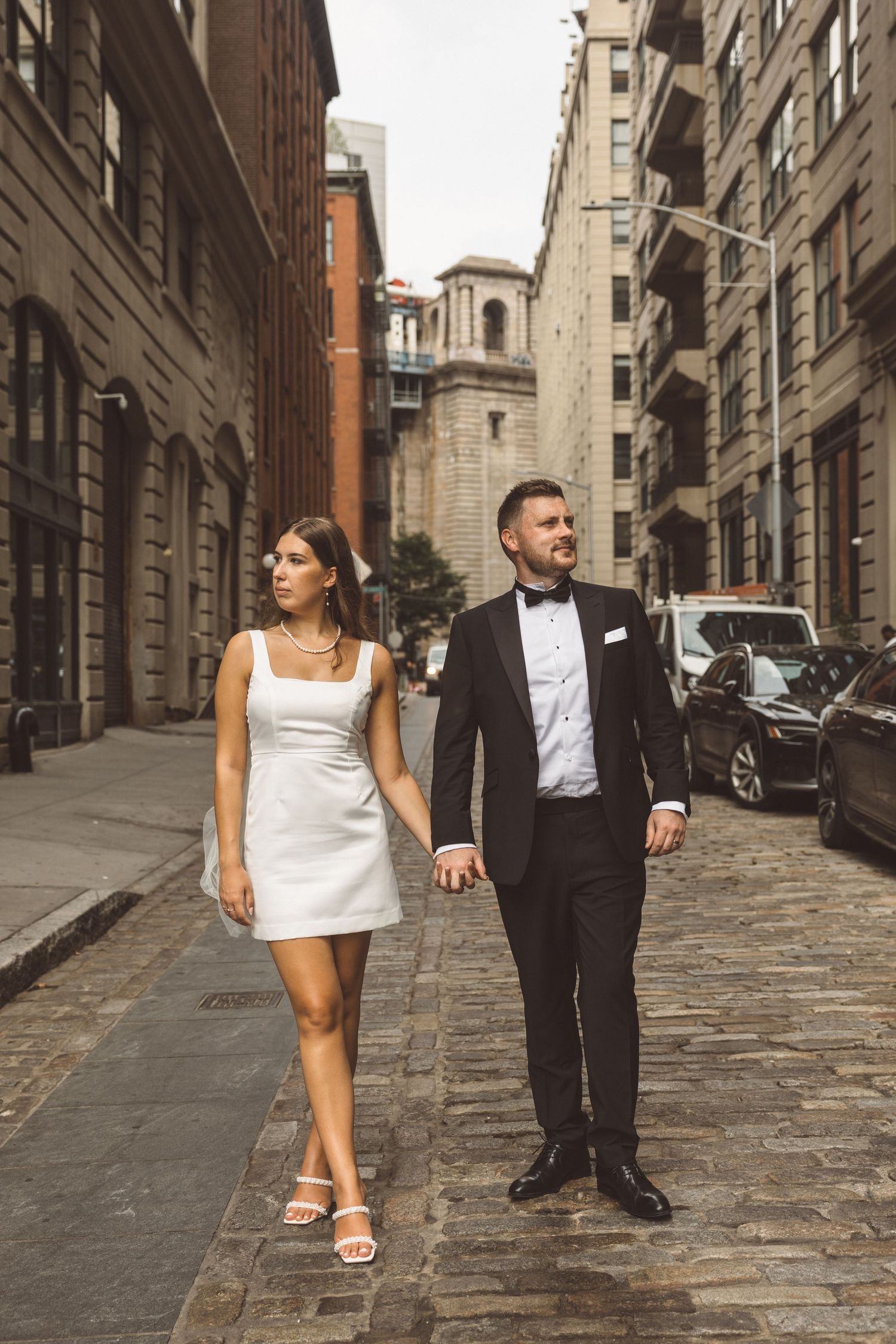 Editorial-style photo of couple holding hands on cobblestone street in NYC