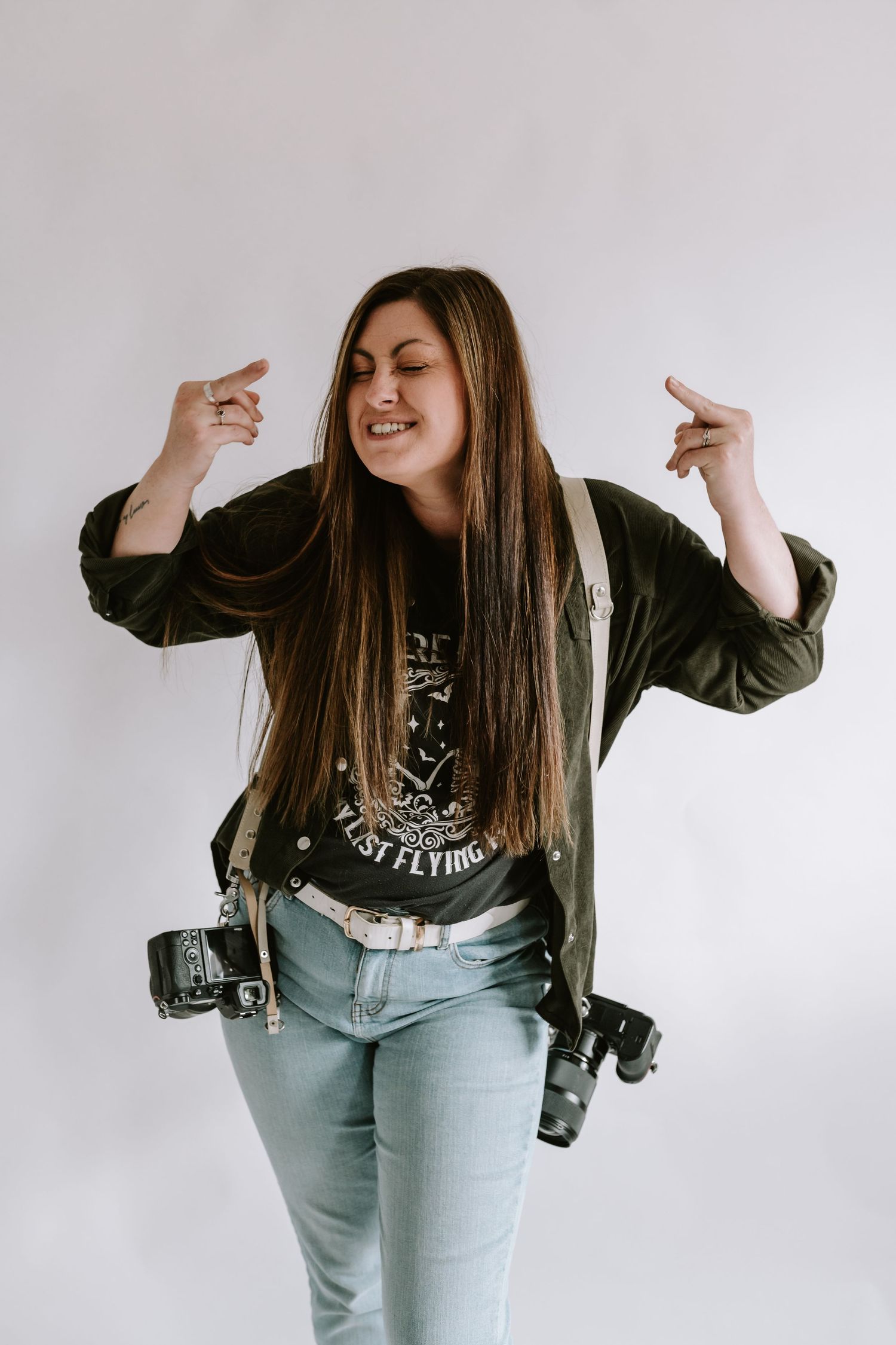 Dancing sequence with long brown hair and wearing a black jacket and light blue jeans against a white backdrop.