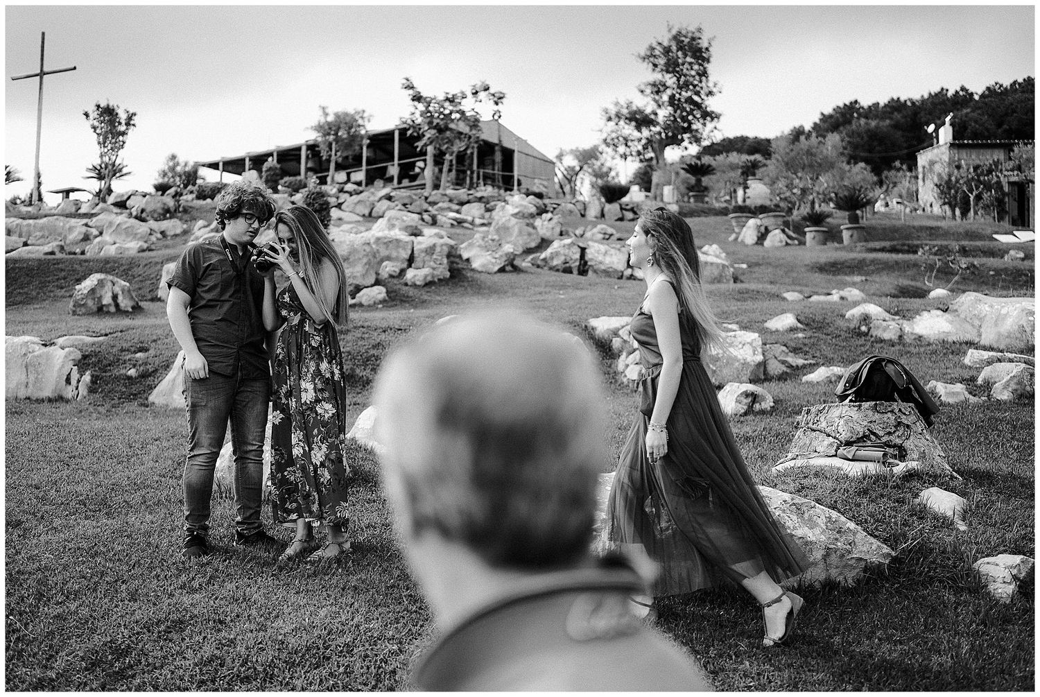 Black and white photo showing people standing in an outdoor garden area with scattered rocks and stones.