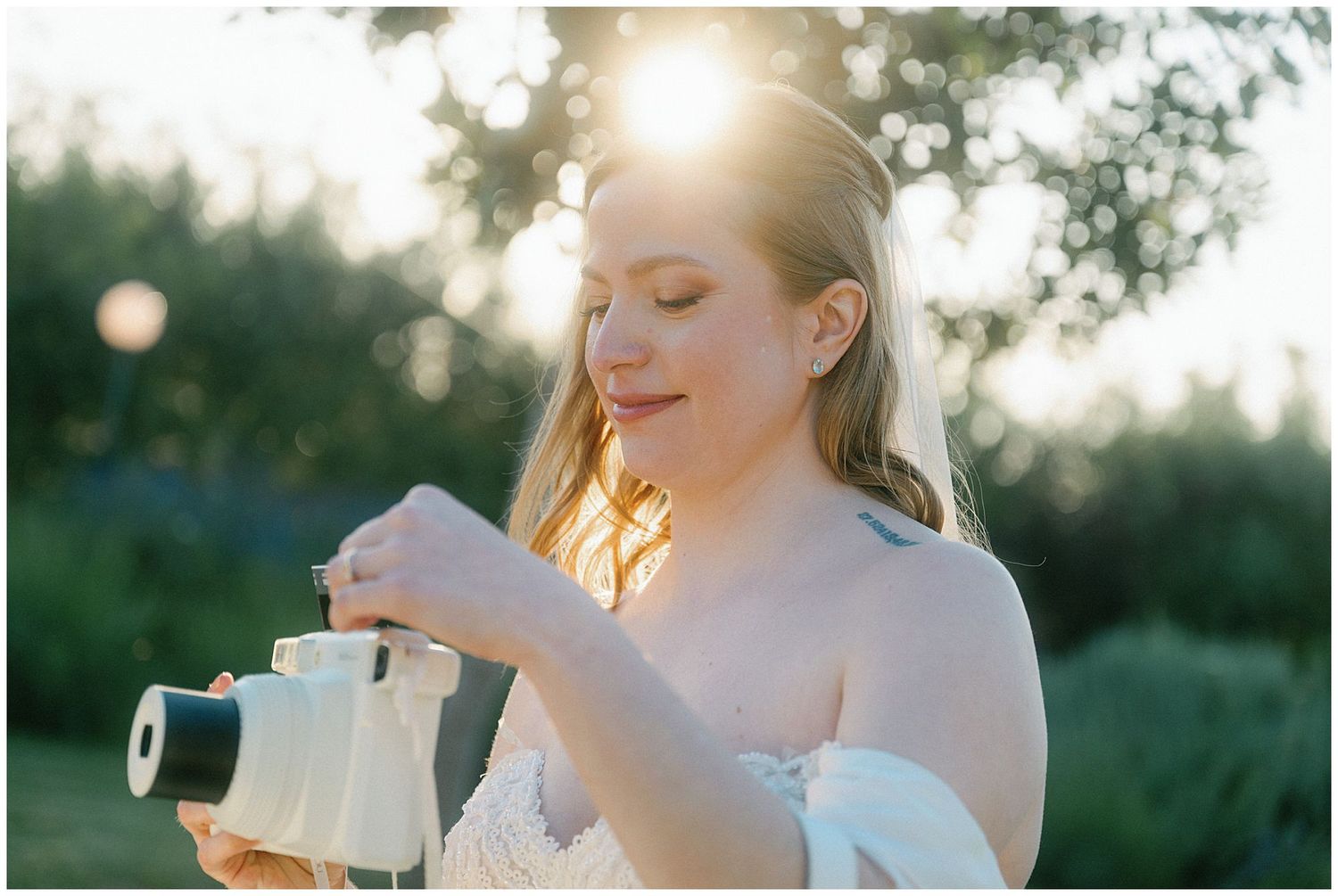 A photographer adjusts their vintage camera in golden sunlight during sunset with a serene natural backdrop.