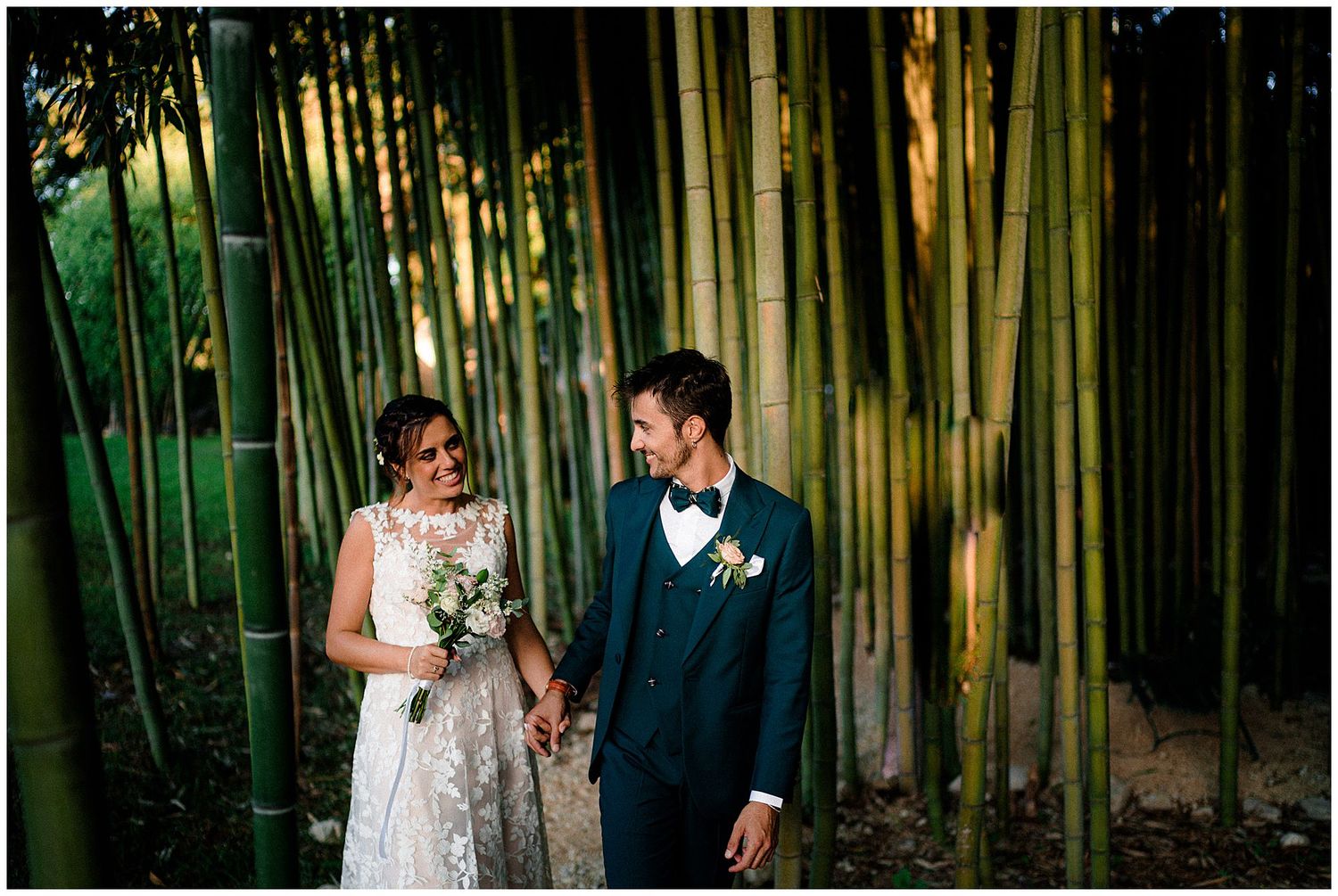 Bride and groom share intimate moment in sunlit bamboo forest.