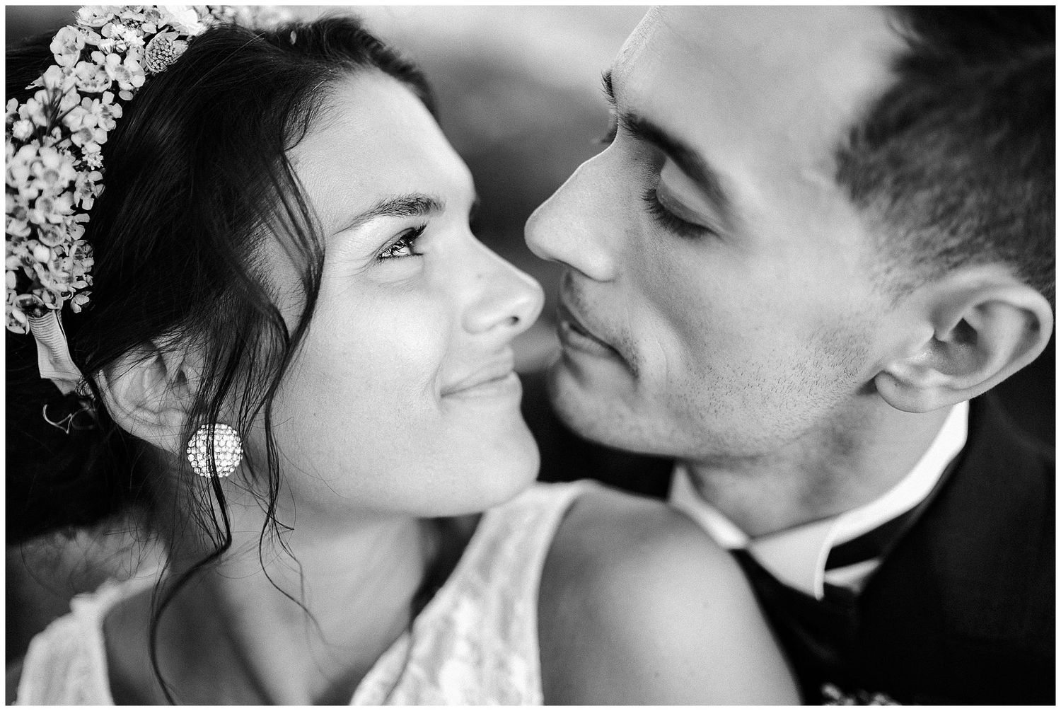 A romantic black and white close-up photograph of newlyweds sharing an intimate moment with their faces close together.