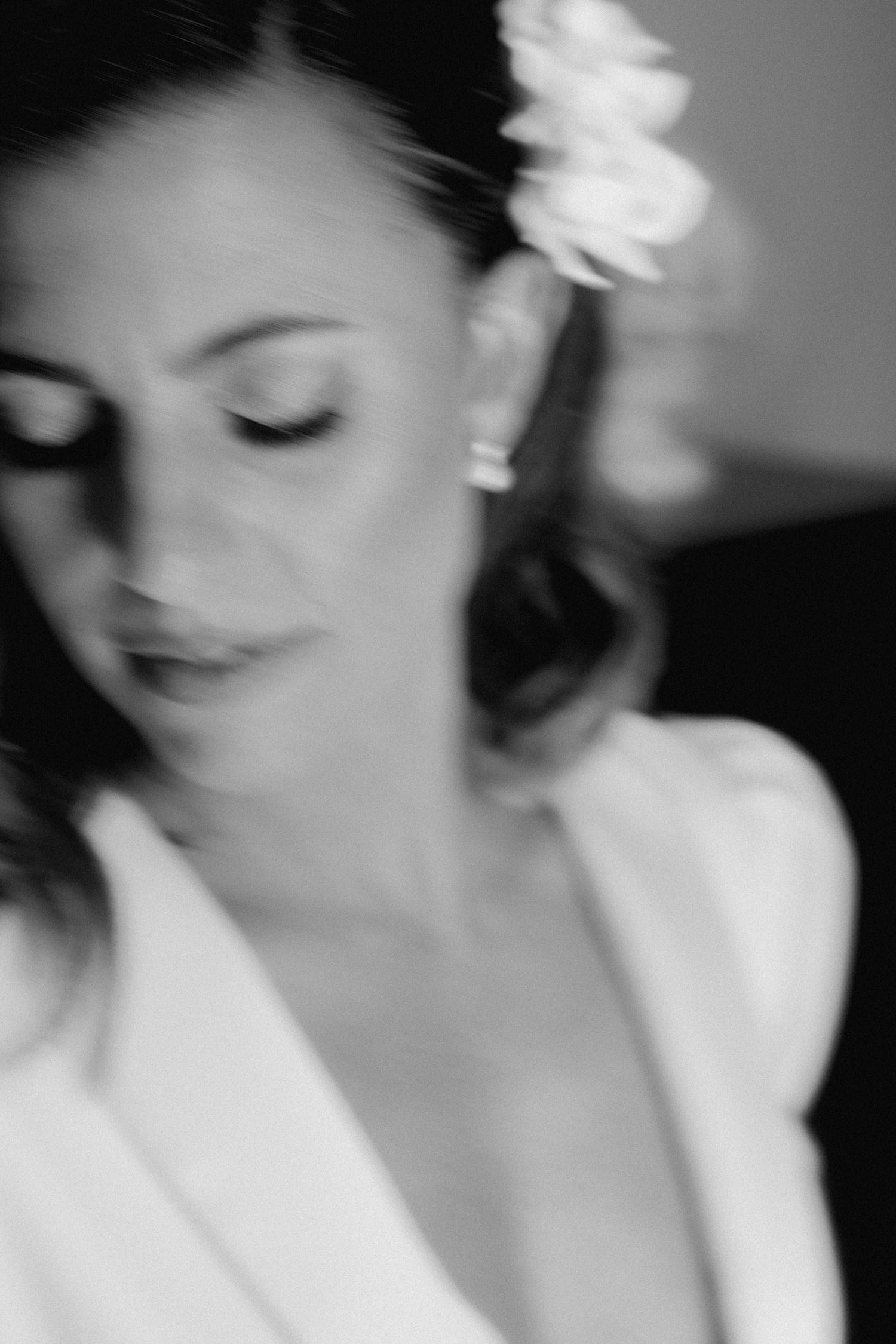 Ethereal black and white portrait of bride with soft focus and white flower in hair.