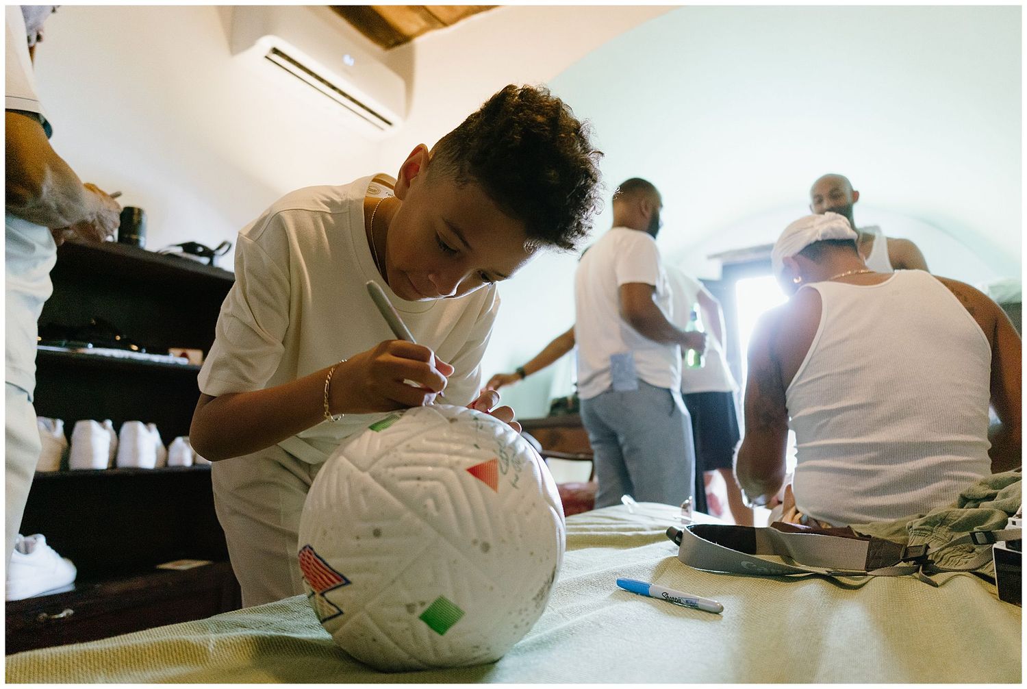 Person carefully drawing and decorating a white spherical object at a table in a bright room.