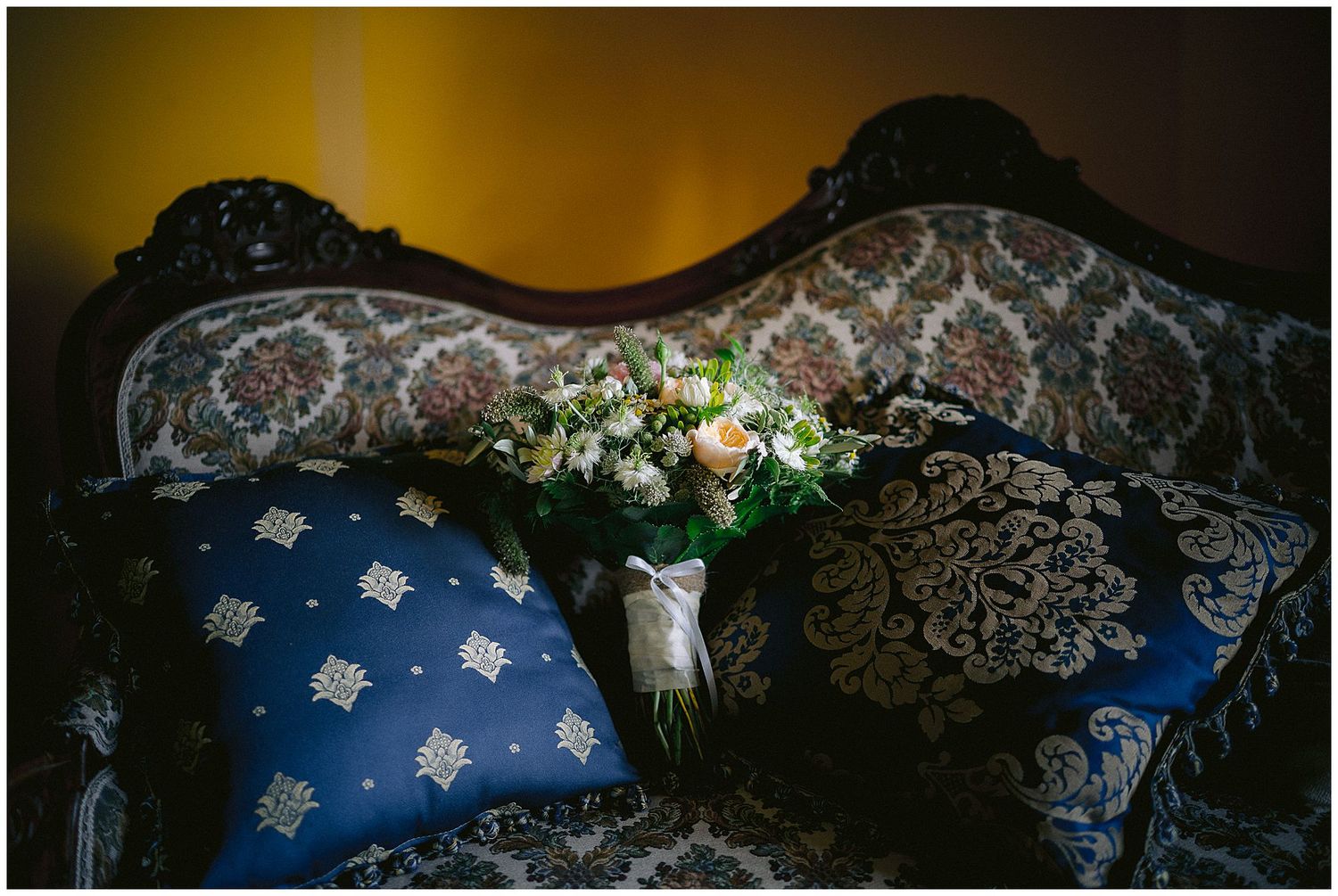 Classic white lace and delicate floral patterns decorate wedding dresses hanging on display against a blue background.