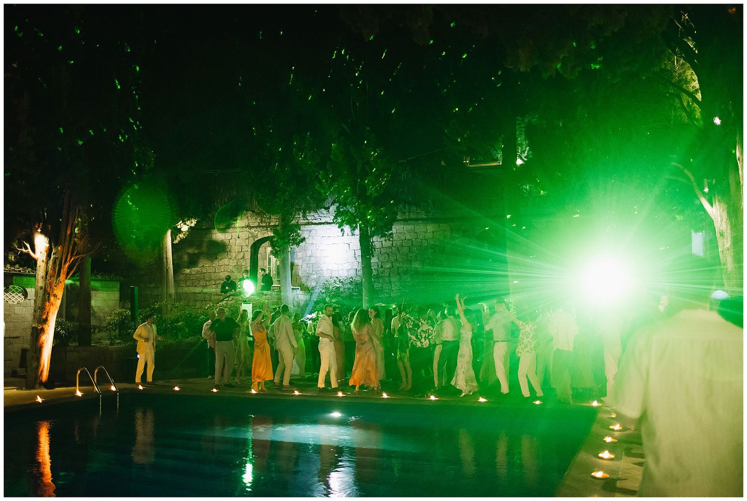 People dancing at a nightclub with bright green lights illuminating the dance floor creating an energetic atmosphere.