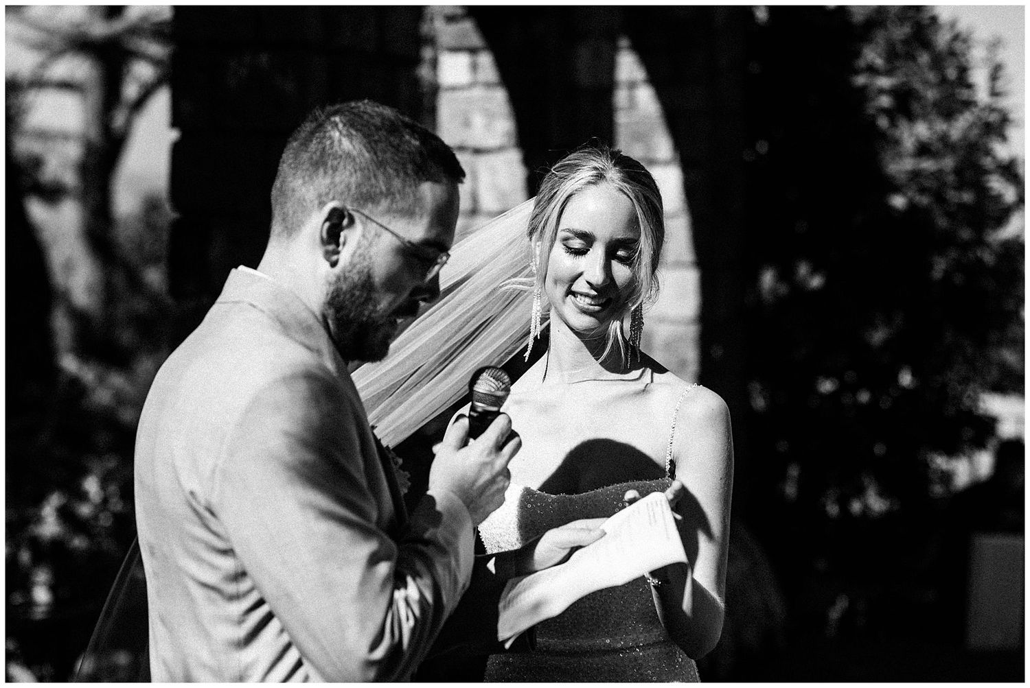 A couple shares an emotional moment while reading documents together in black and white photography outdoors.
