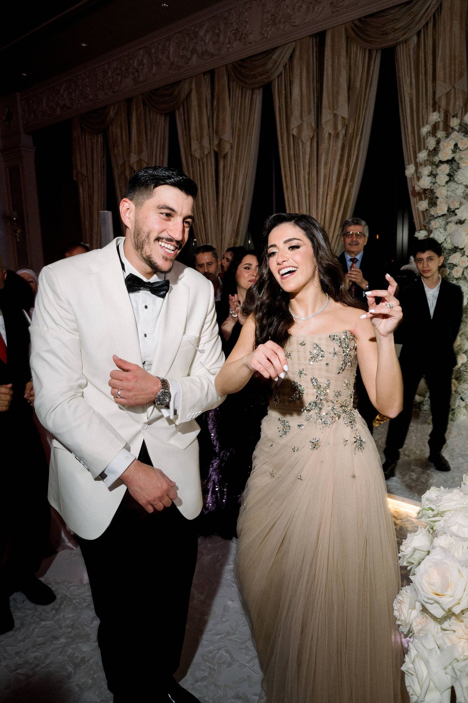 A joyful wedding reception moment on the dance floor with a couple in formal attire laughing and dancing together.
