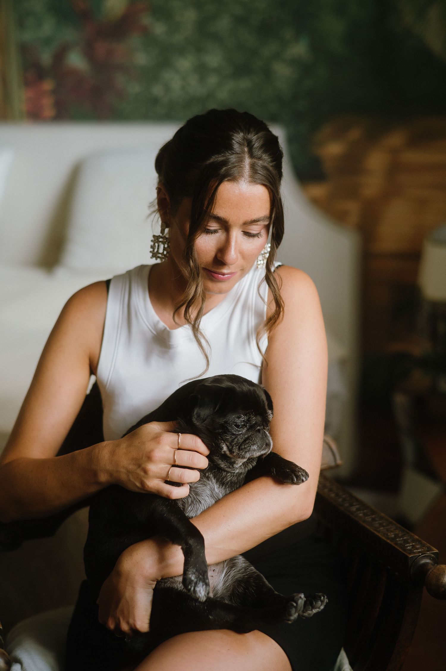 A tender moment captured as someone in white holds and pets a dark-colored cat.