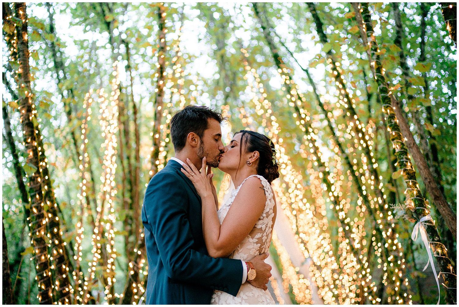 Newlyweds sharing intimate moments in a magical forest setting with twinkle lights.