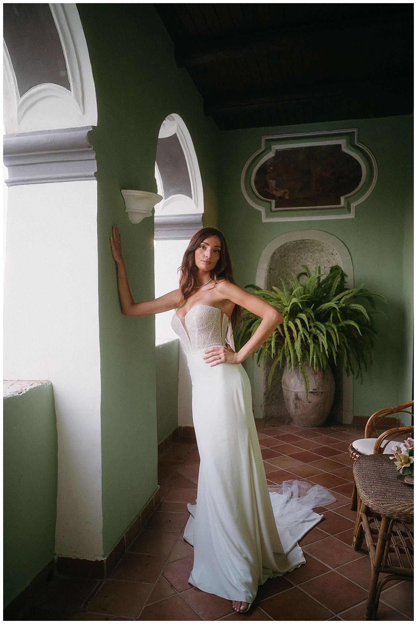 Elegant wedding dress photography in a Mediterranean-style venue with arched doorways and green walls.