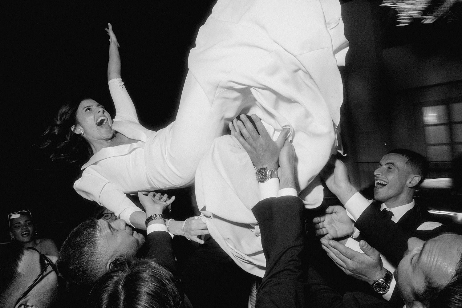 Black and white photo of bride crowd surfing during wedding reception.