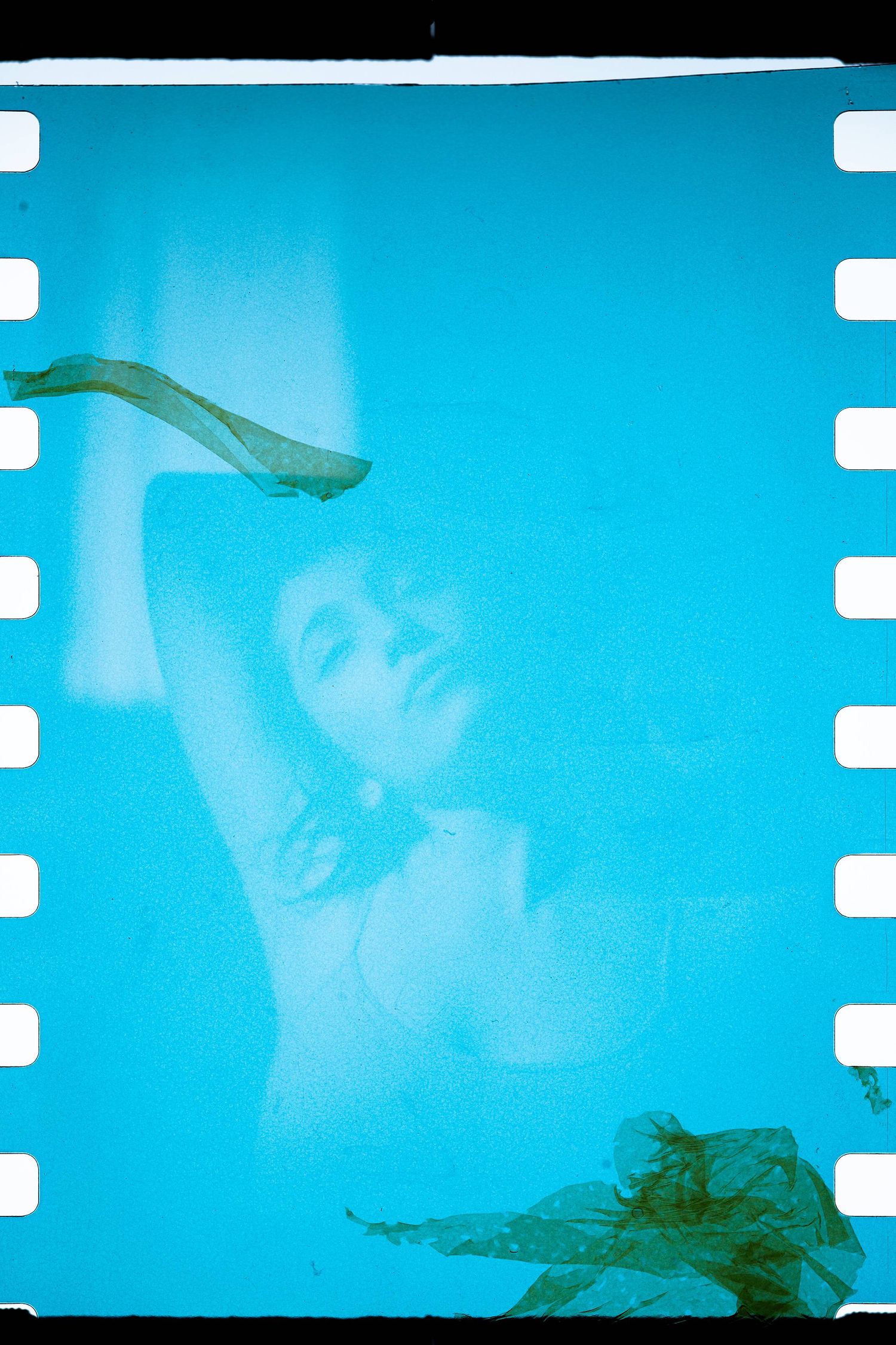 Ethereal blue film photograph with flowing fabric and dreamy double exposure effect.