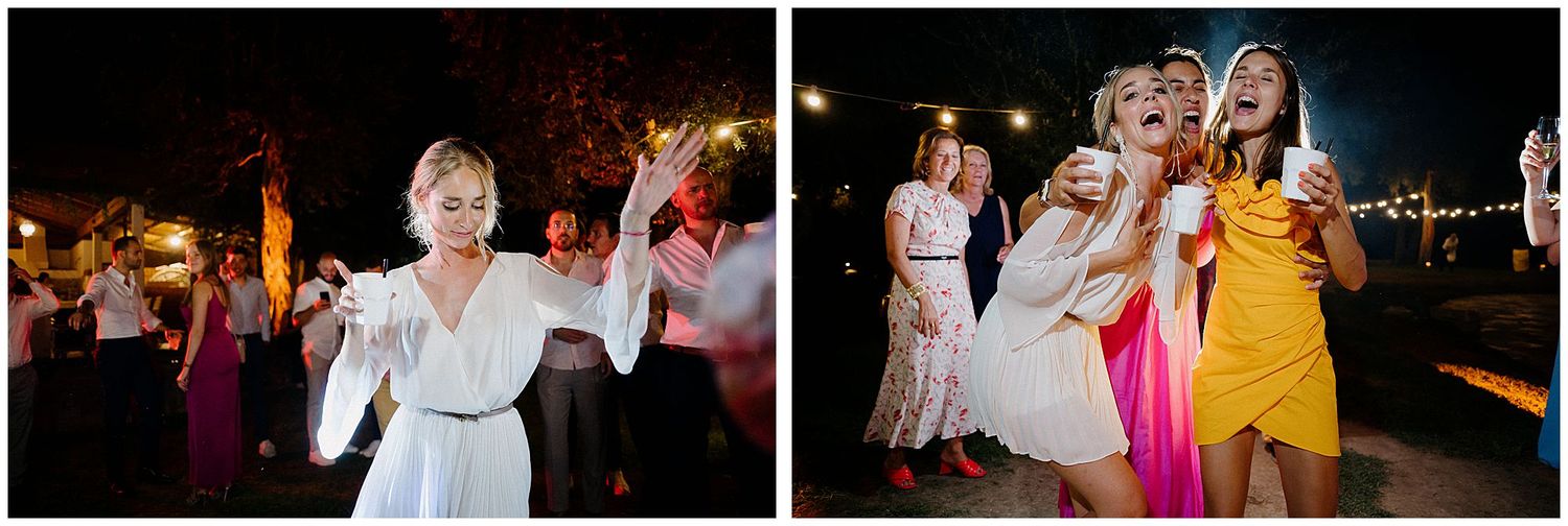 Wedding party guests dance and celebrate at night during outdoor reception with festive string lights.