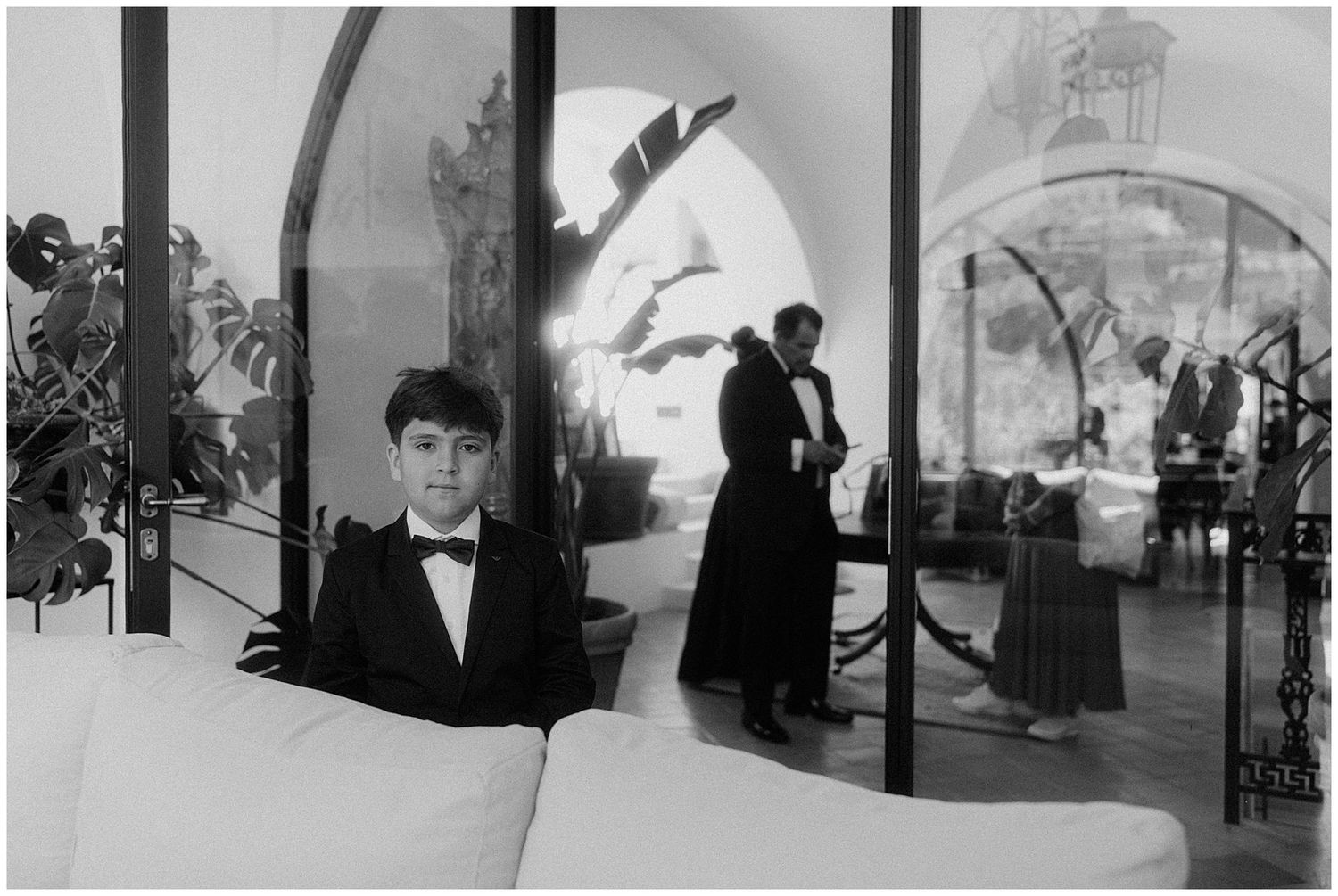 Visitors explore a modern architectural space with curved glass walls and archways in black and white photography.