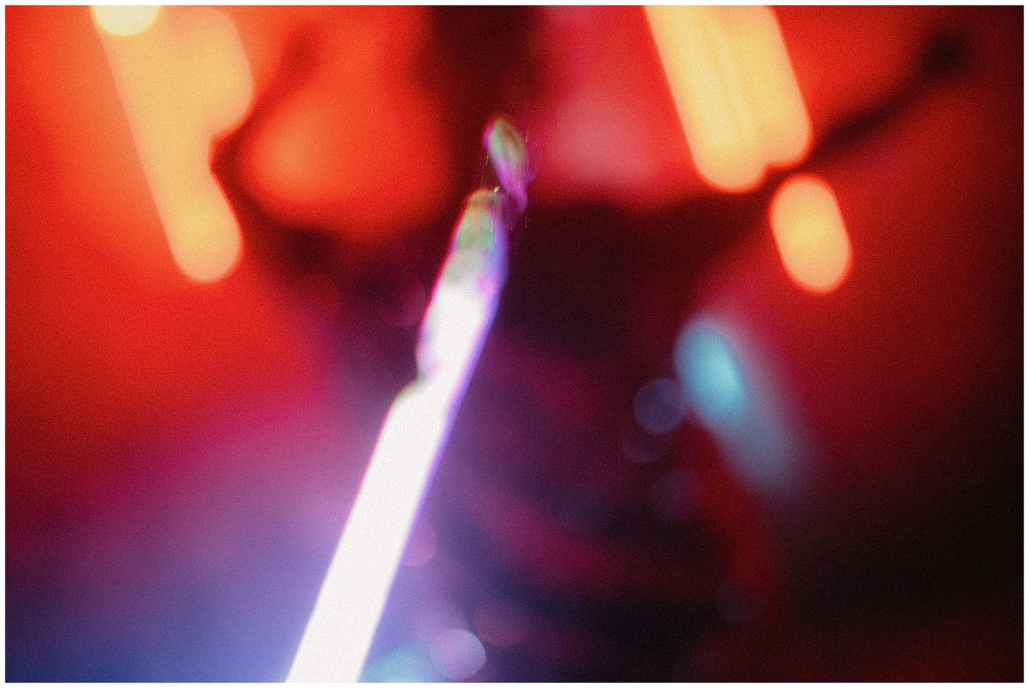 A glowing neon light creates a soft purple and blue streak against a blurred red background.
