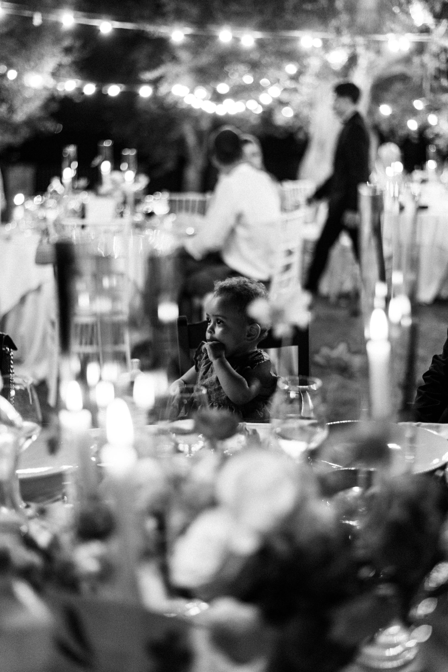 Candlelit reception table with bokeh lights and floral centerpieces creating a romantic evening atmosphere.