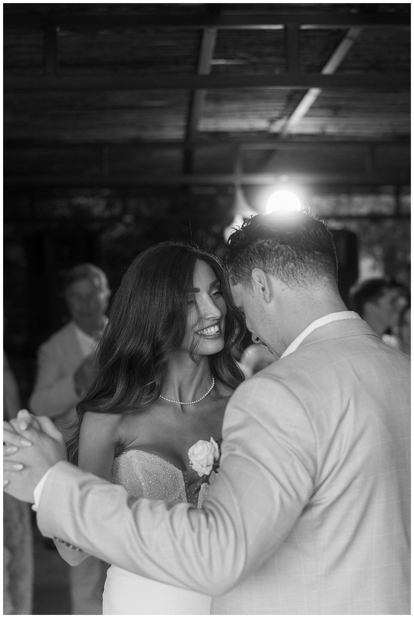 Black and white candid photo of a dancing couple sharing an intimate moment at their wedding reception.