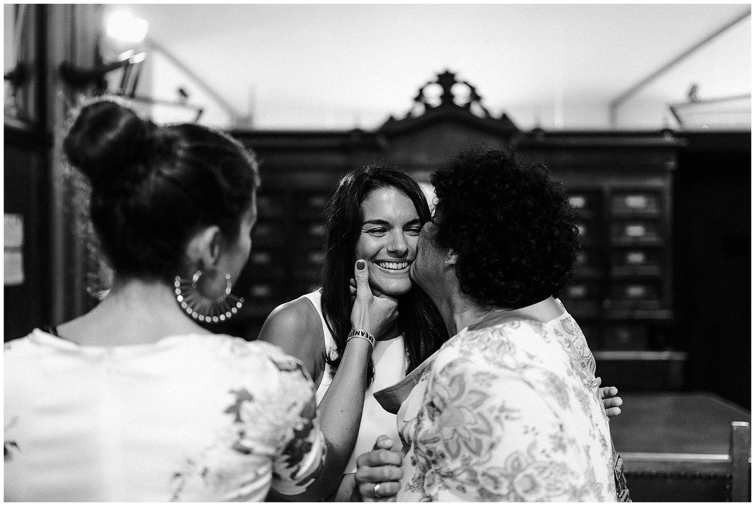 Three people engaged in an intimate conversation share a joyful moment together in black and white.