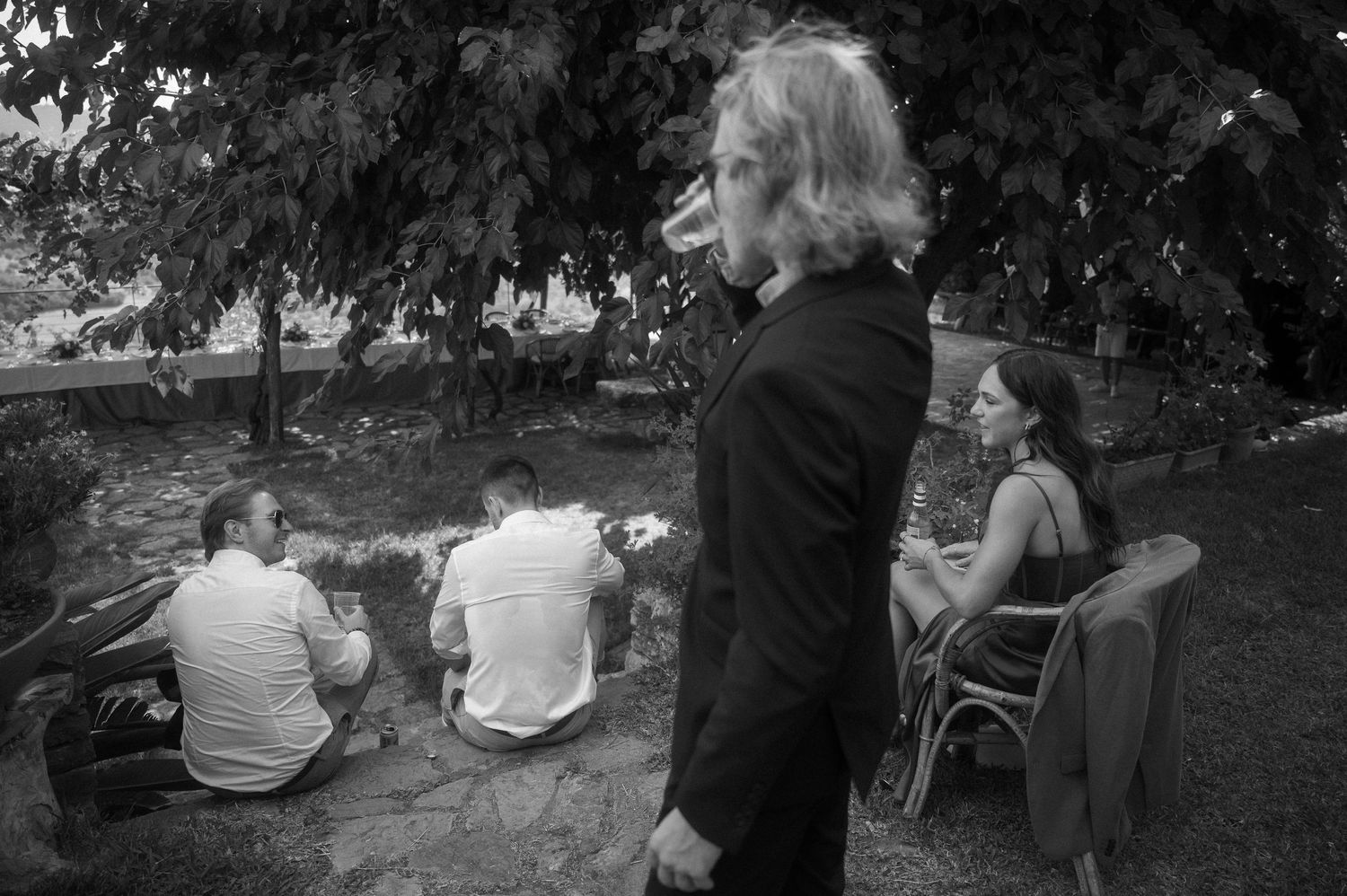 Black and white photo of people gathered outdoors in a casual garden setting.