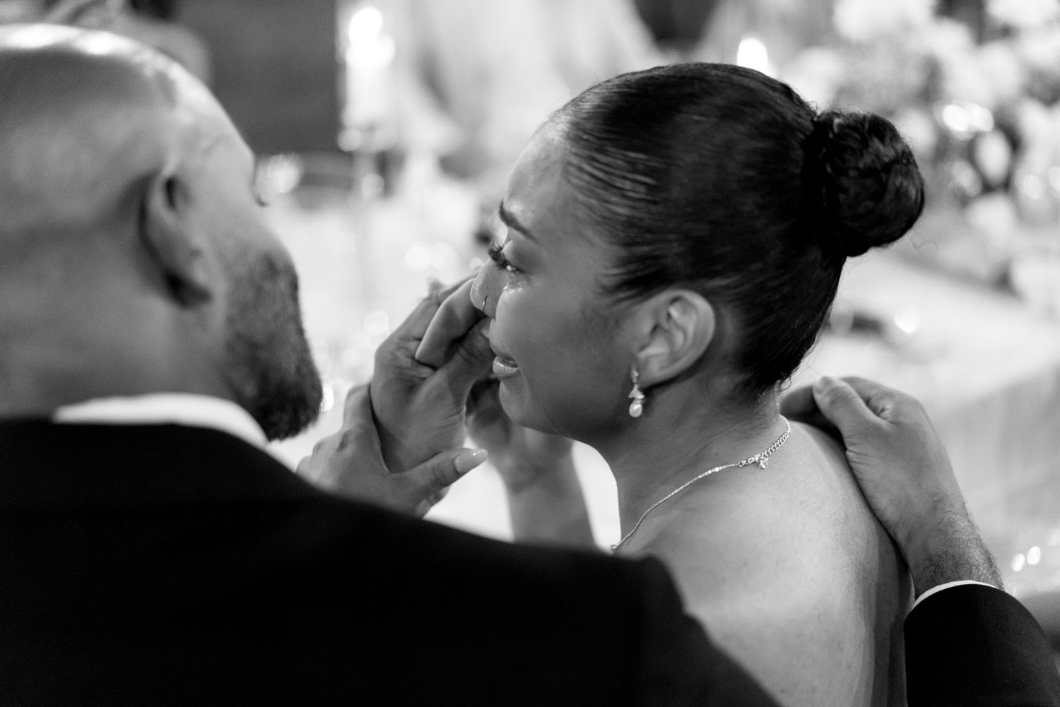 An emotional black and white wedding moment captured between a bride being touched on the cheek by the groom.