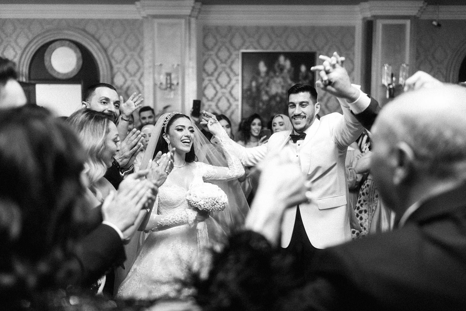 A black and white photo of jubilant wedding celebration with guests celebrating and dancing at a vintage reception.