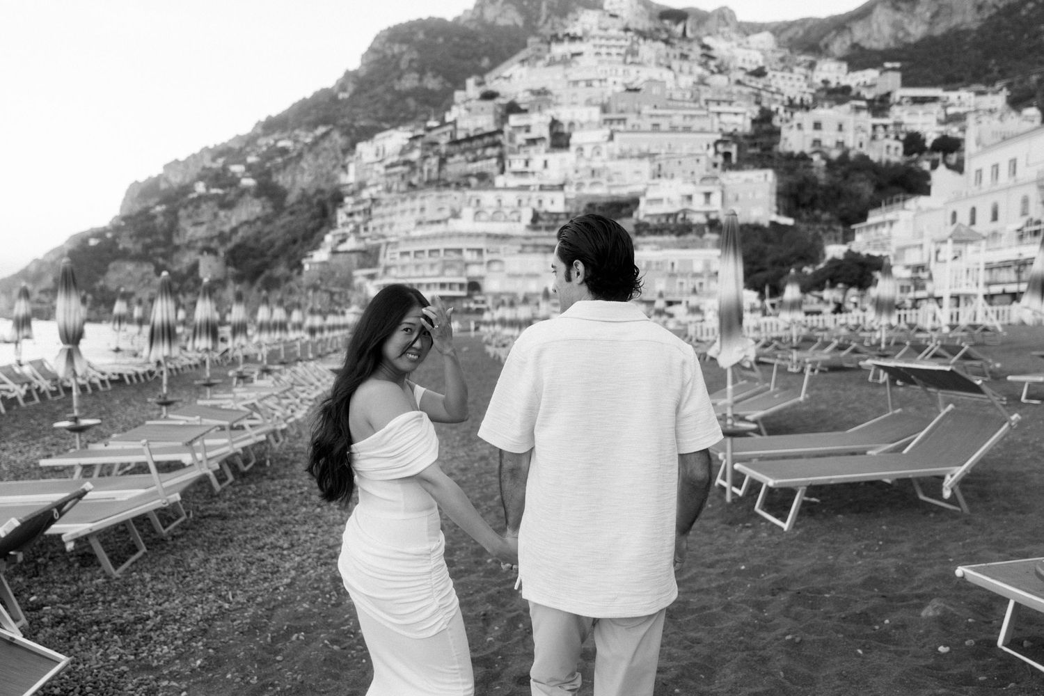 Black and white photo of couple overlooking coastal town of Positano Italy.