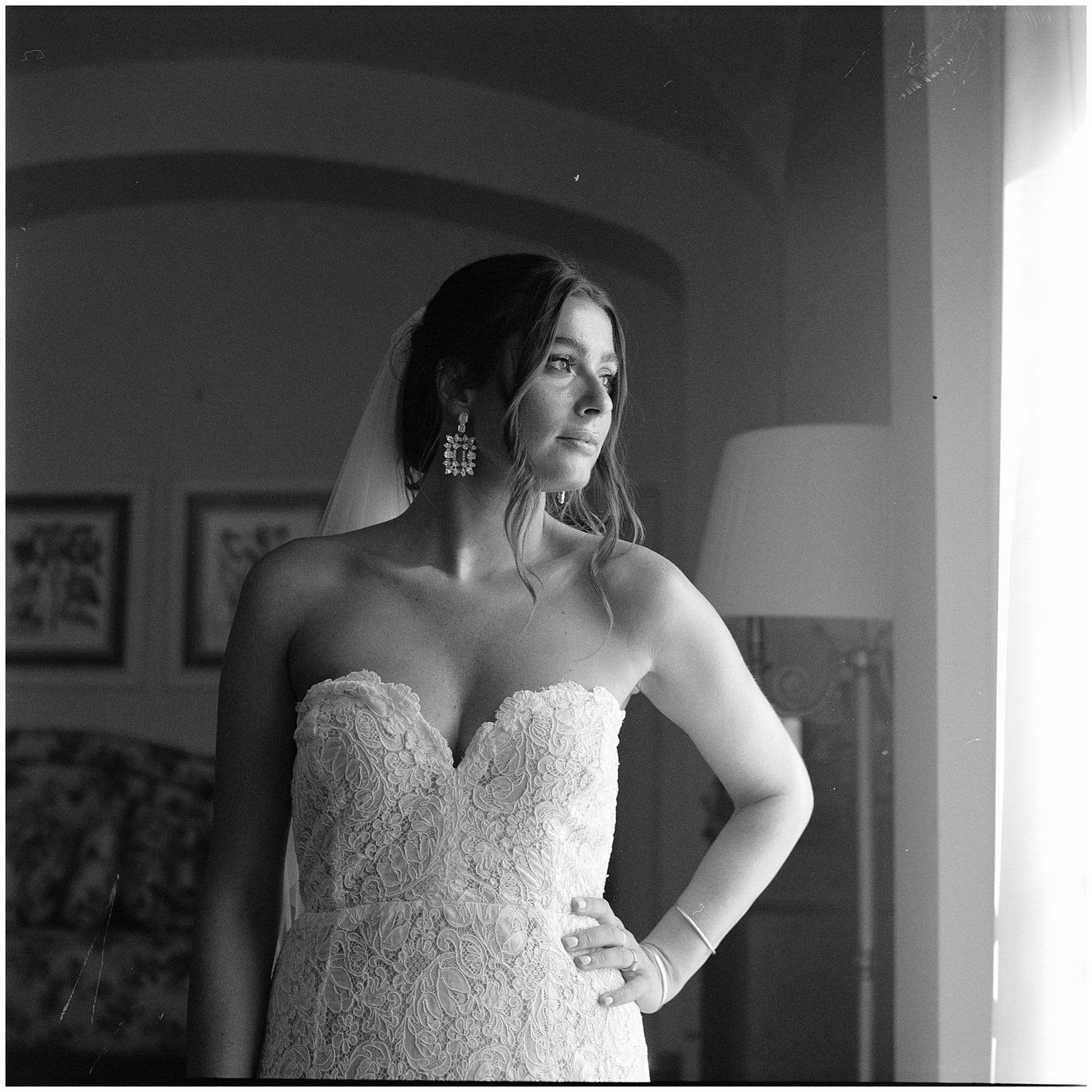 Black and white portrait of a bride in a strapless lace wedding gown with sweetheart neckline gazing to the side.