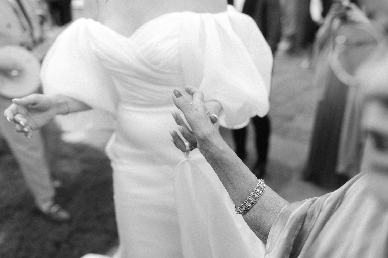 Close-up detail shot of hands adjusting the waist of a white wedding dress.