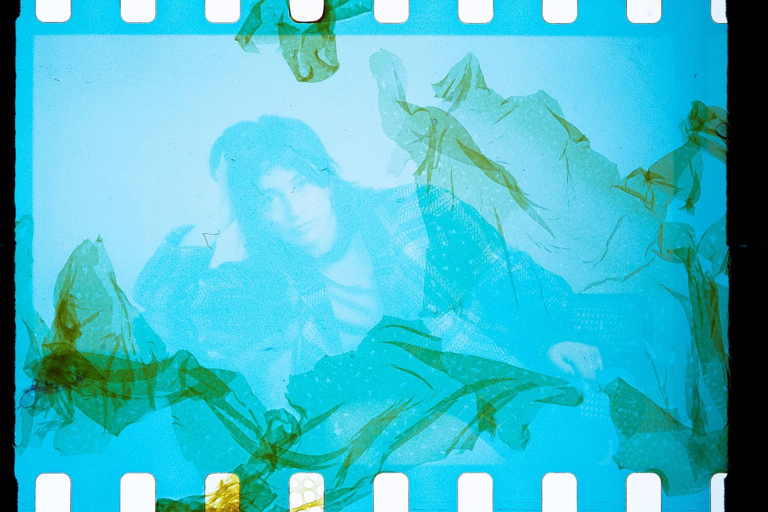Dreamy double exposure photograph in blue and green tones showing overlapping plant leaves and branches.