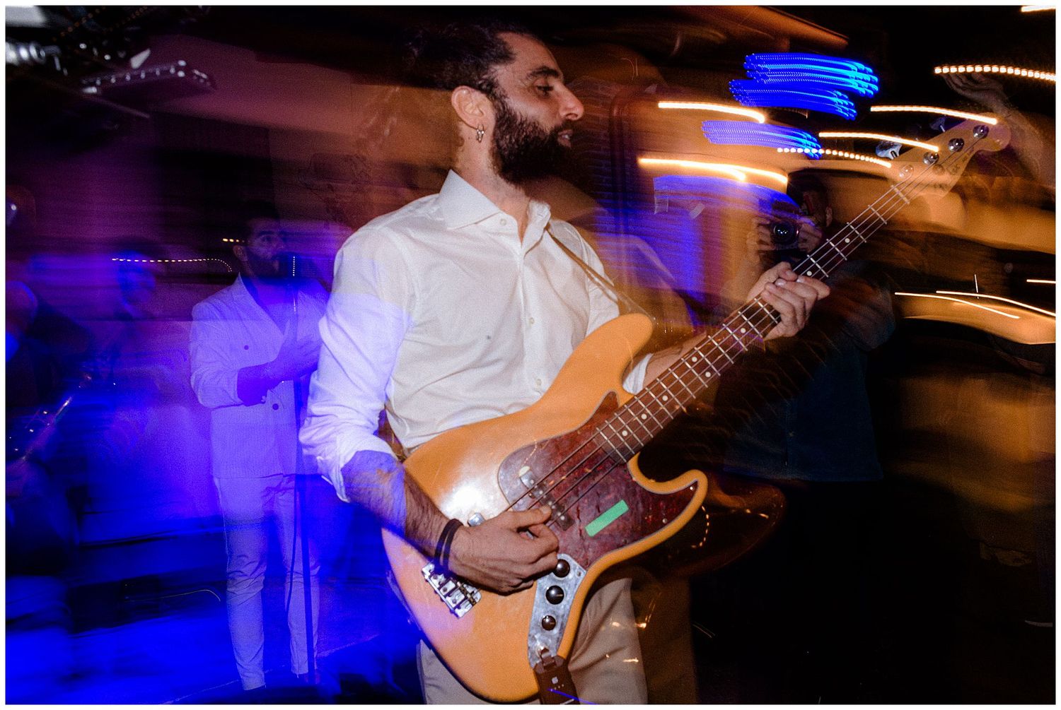 Guitarist performing at a wedding reception with motion blur and colorful lighting effects.
