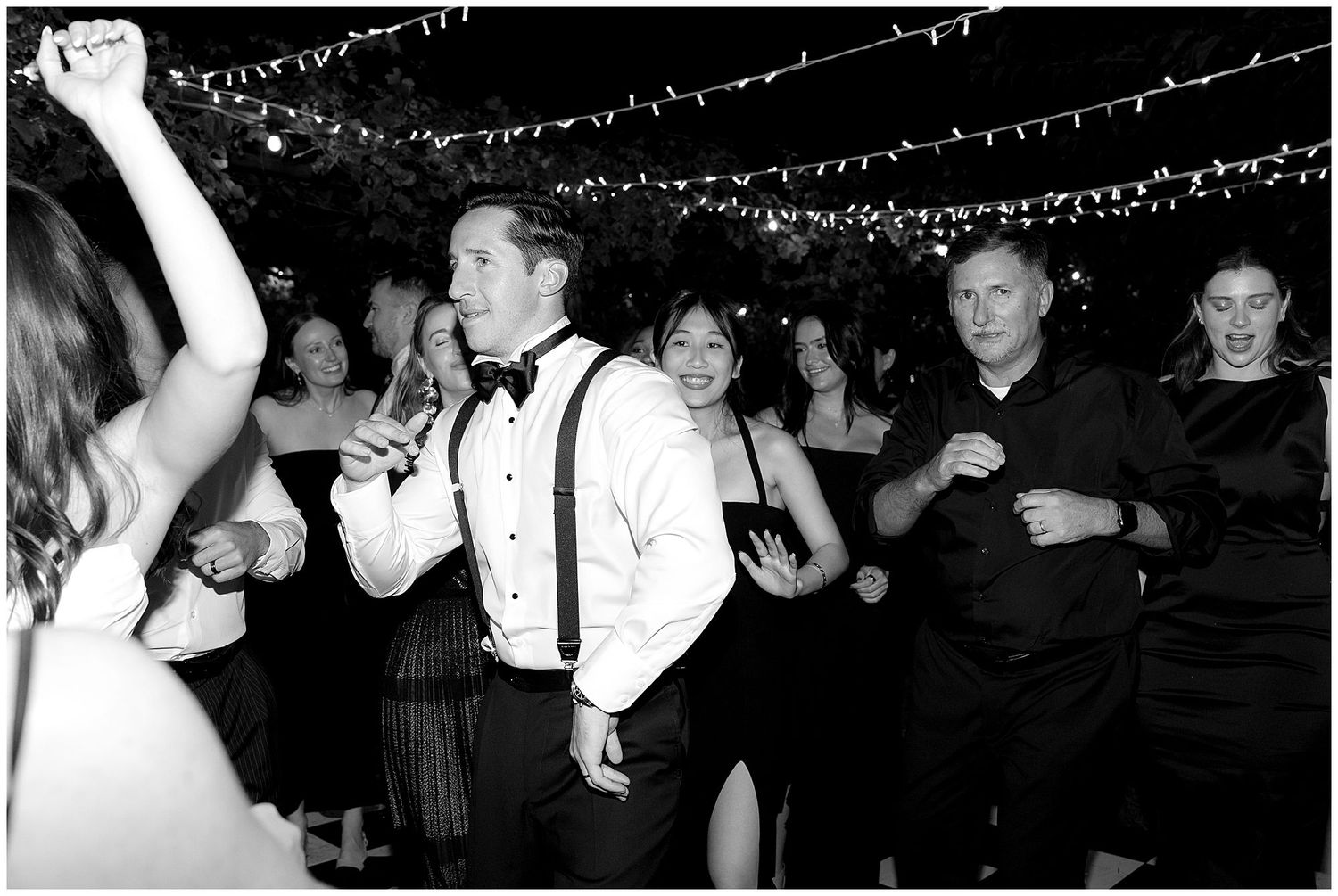 Silhouettes of wedding guests dancing and celebrating on the dance floor under twinkling lights and decorations.