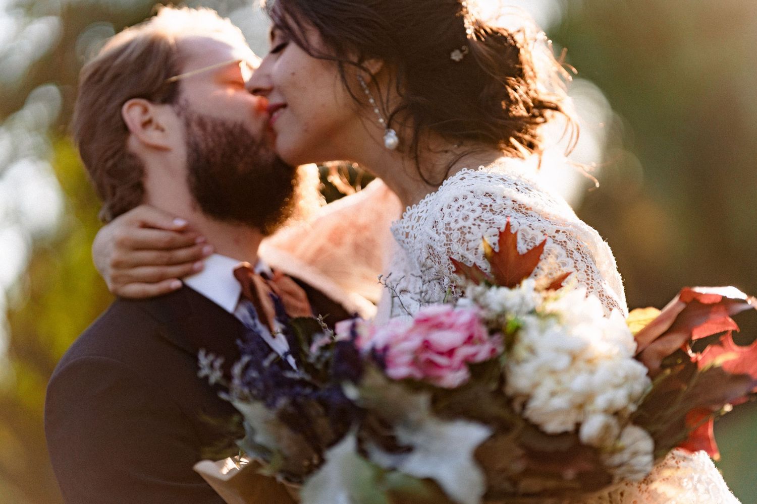 A romantic sunset moment between newlyweds with a colorful floral bouquet in warm golden light.
