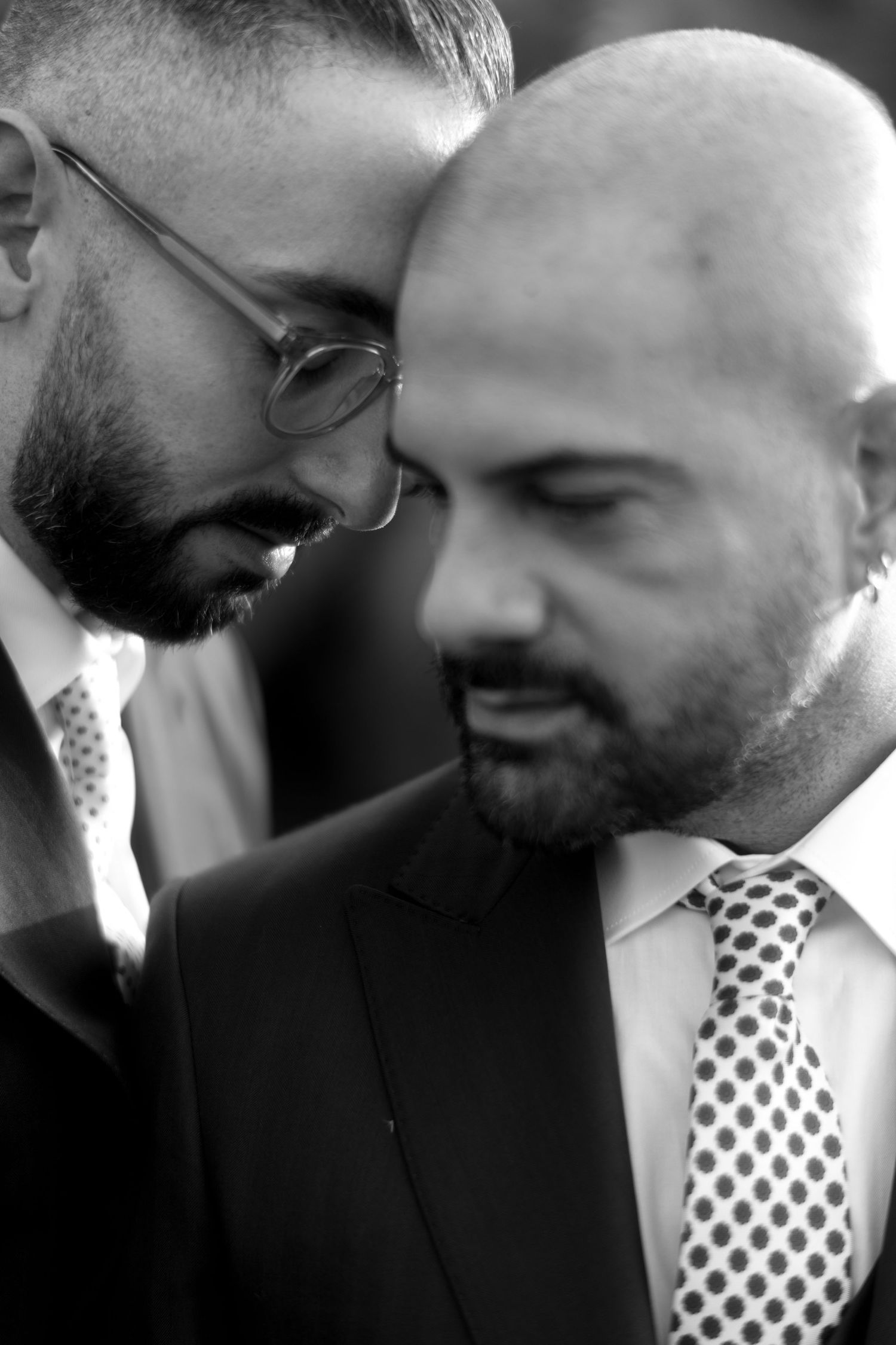 Black and white close-up of two people in suits sharing an intimate moment.