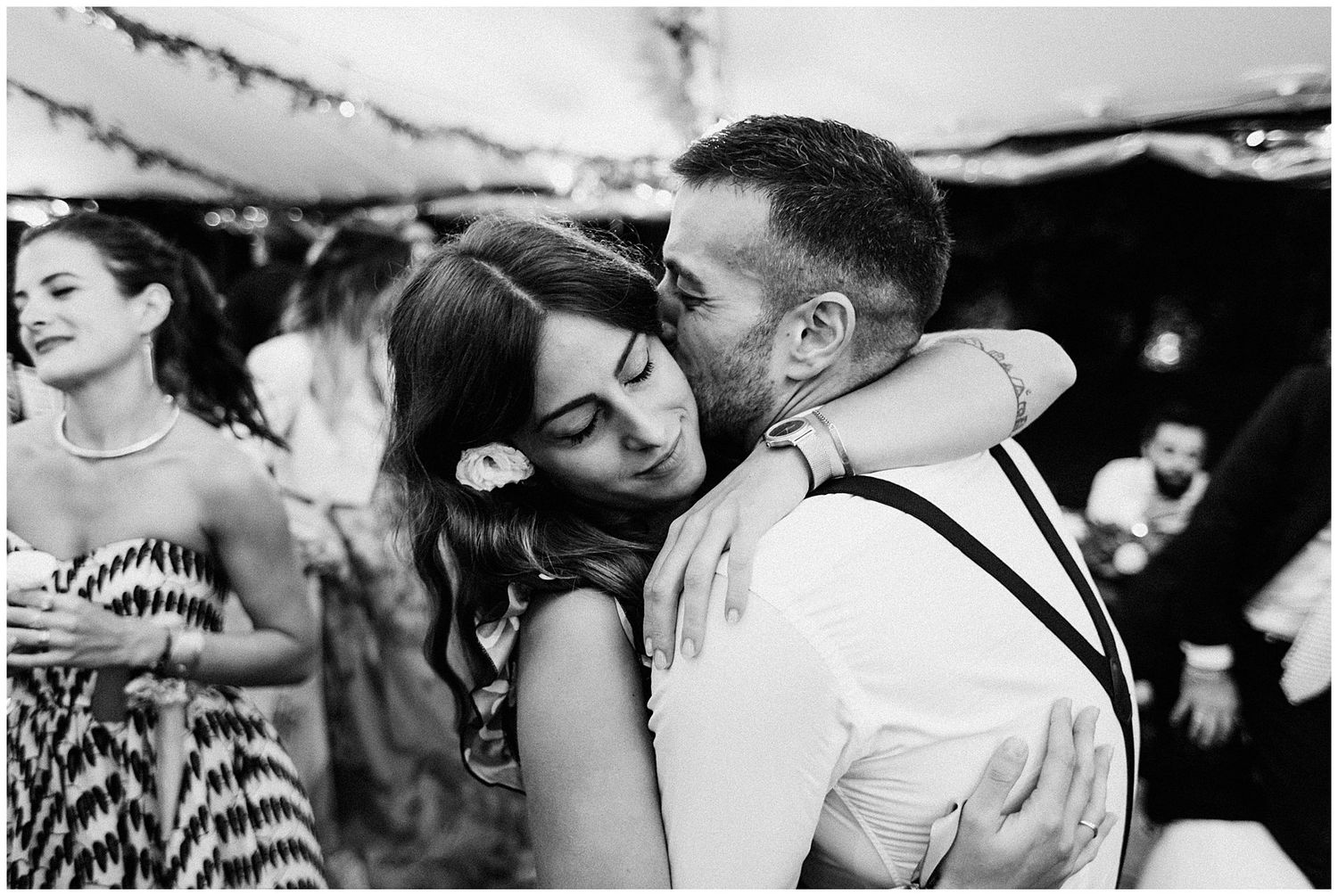Black and white intimate dance moment captured at a wedding reception under twinkling lights.
