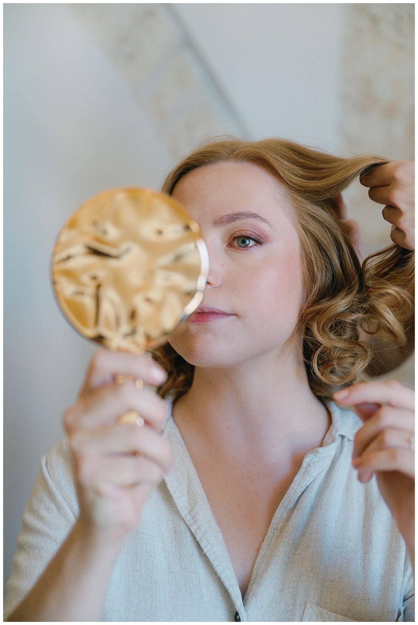 A dreamy portrait of someone holding a golden mirror while getting their hair styled.