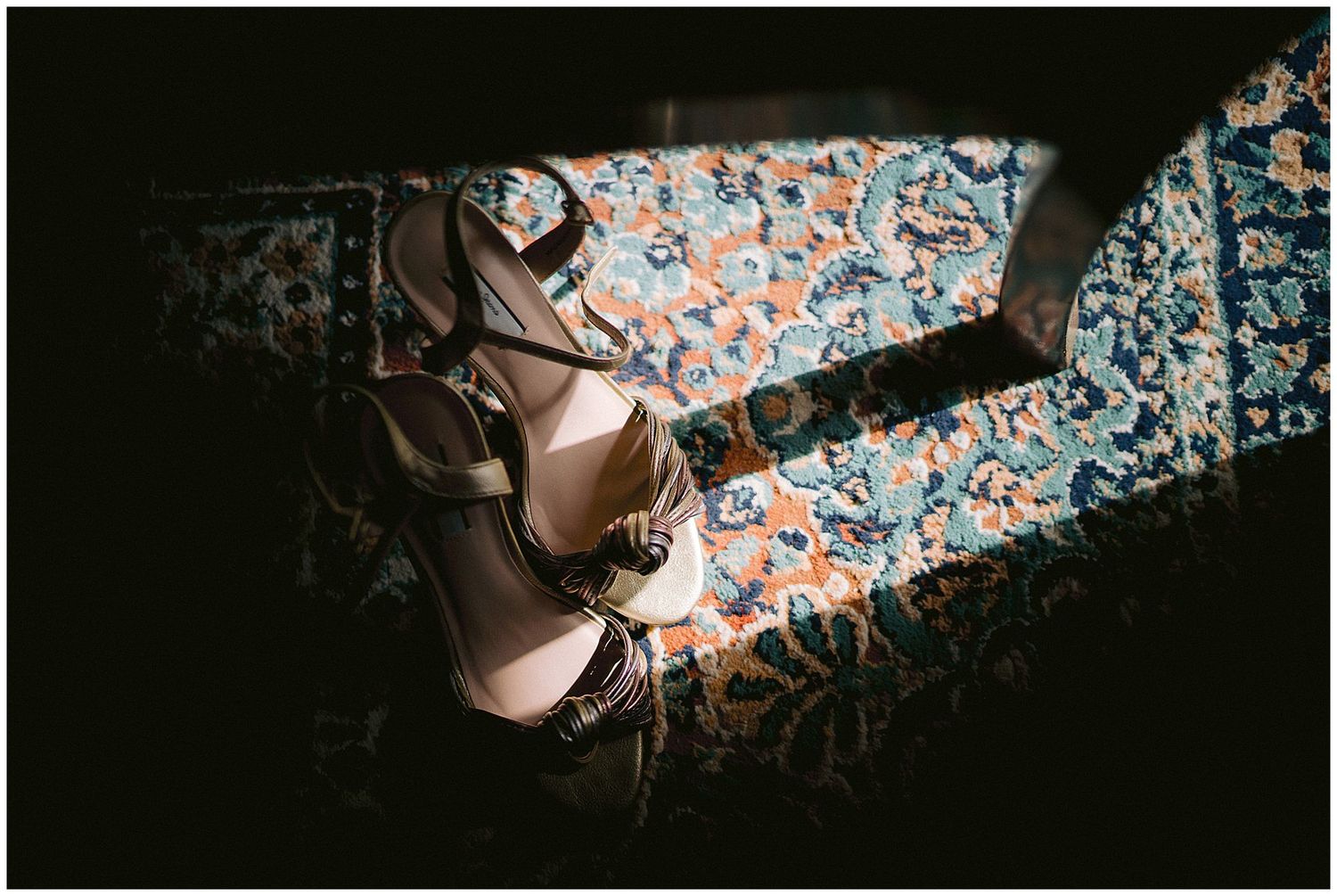 Ballet shoes resting on a floral patterned surface in dramatic lighting with moody shadows.