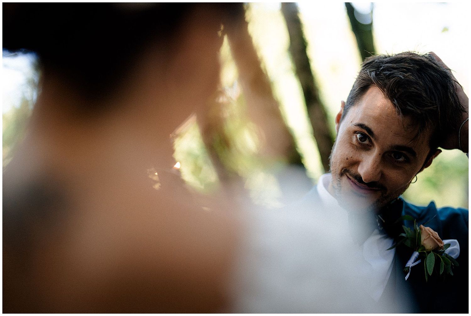 A candid wedding photo showing a participant wearing a boutonniere in soft bokeh lighting.