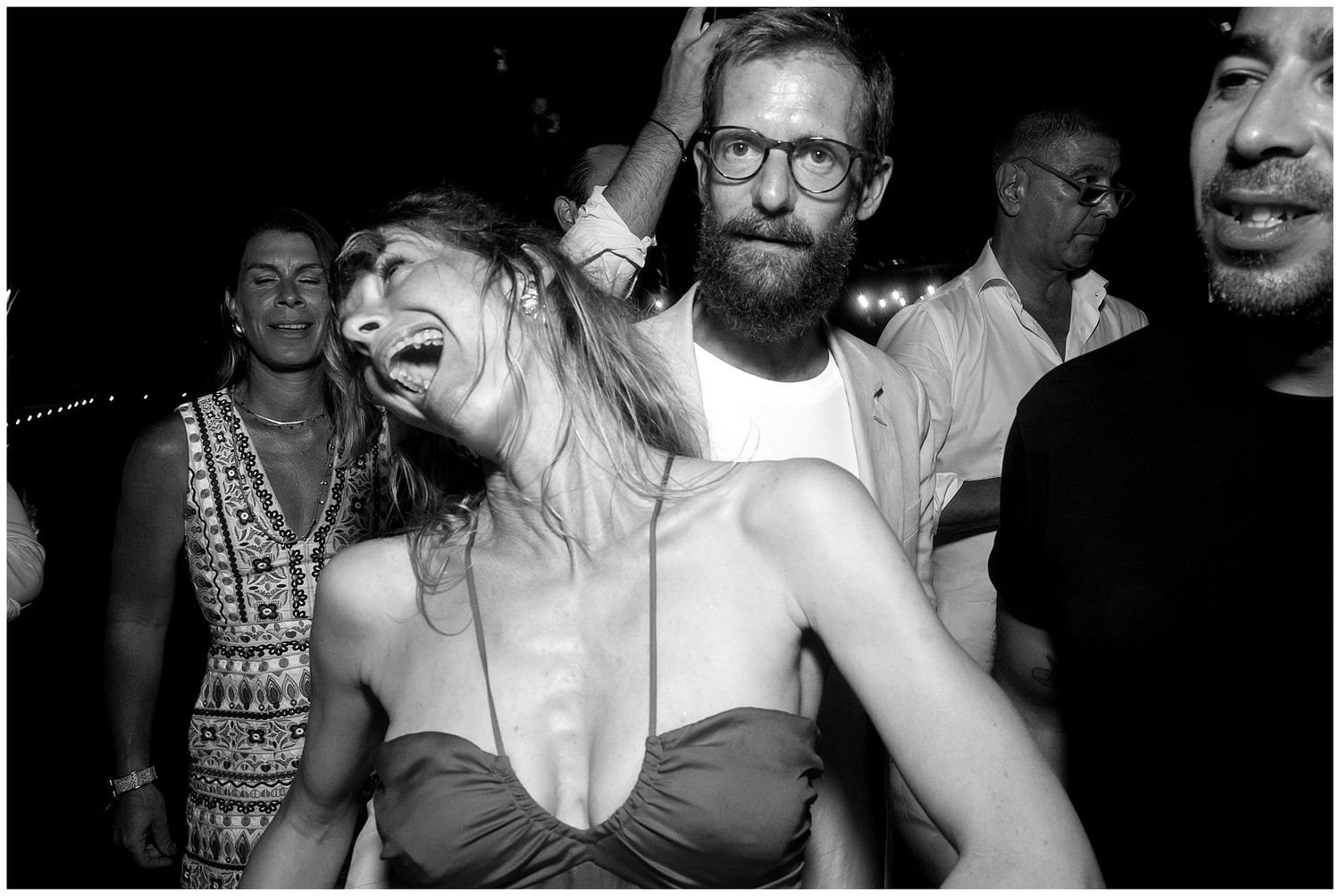 Black and white photo showing joyful dancing people at a nightclub or party.