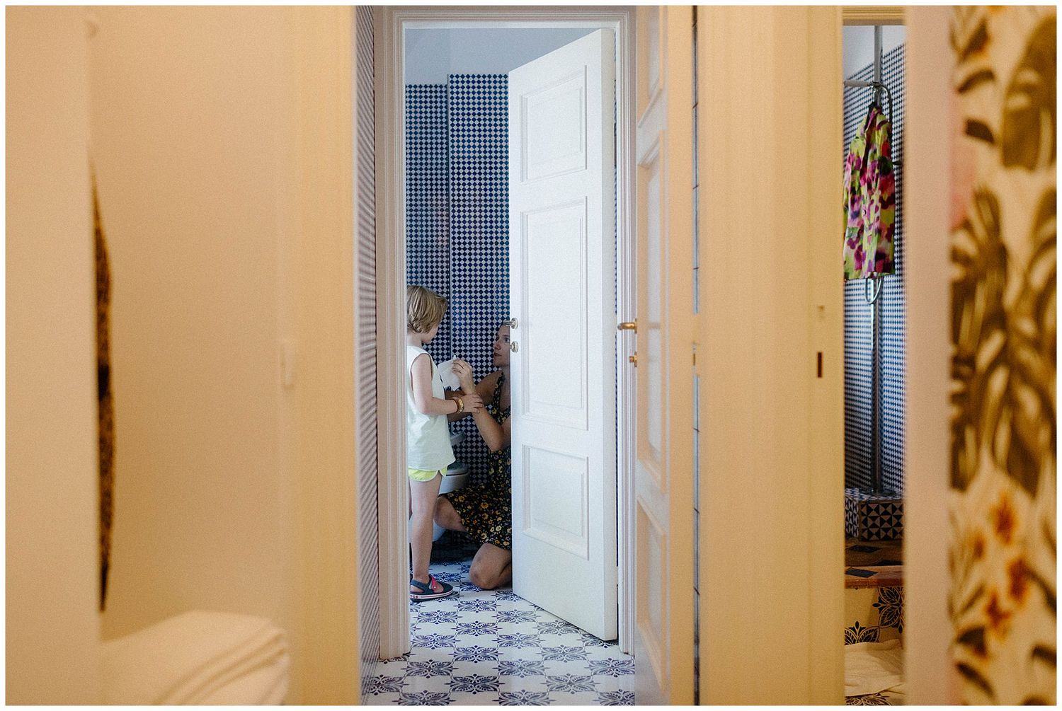 View through doorway showing checkered floor tiles and interior hallway with natural light coming through.