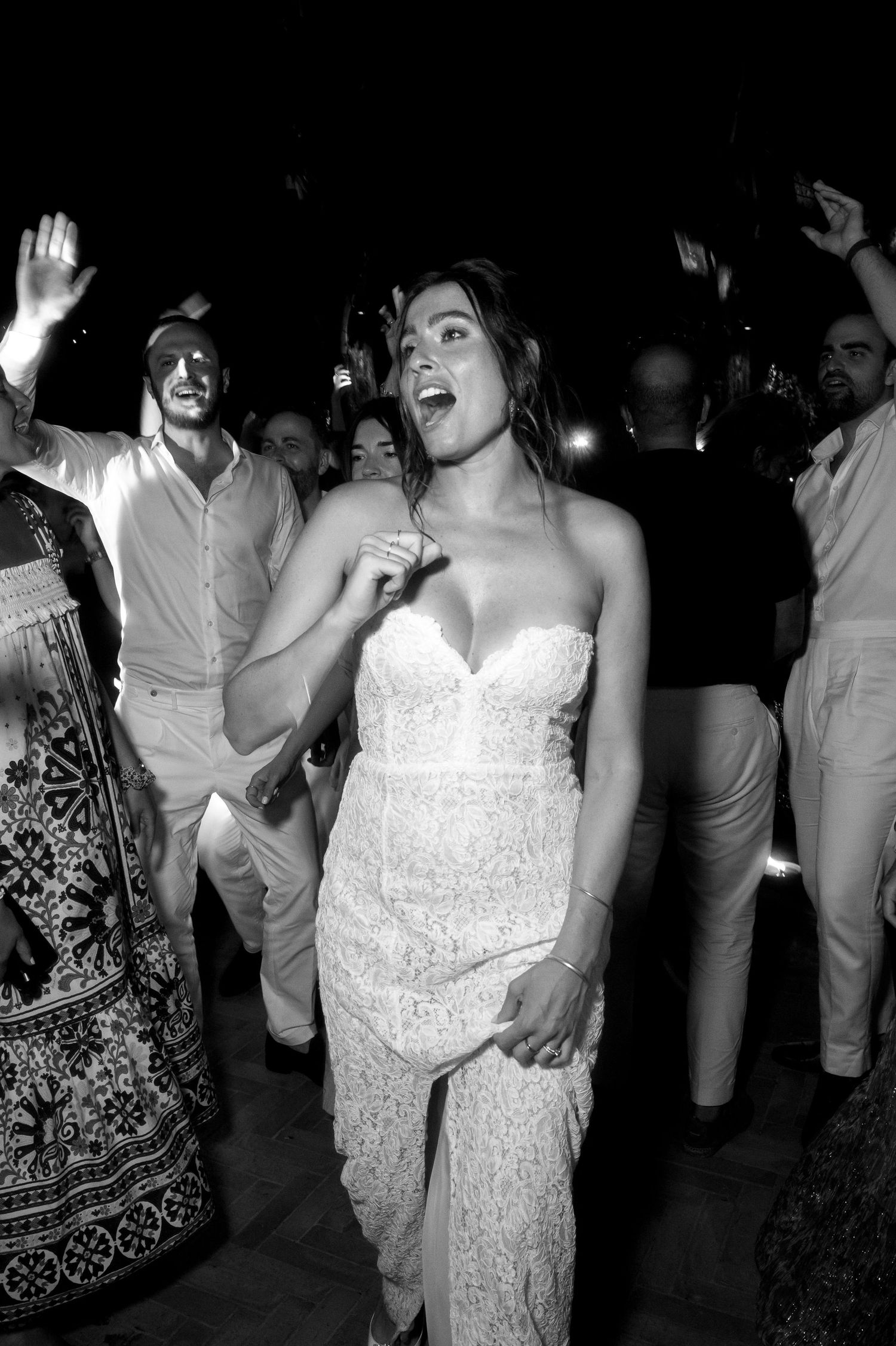 Reception guests dance and celebrate at a nighttime wedding party.